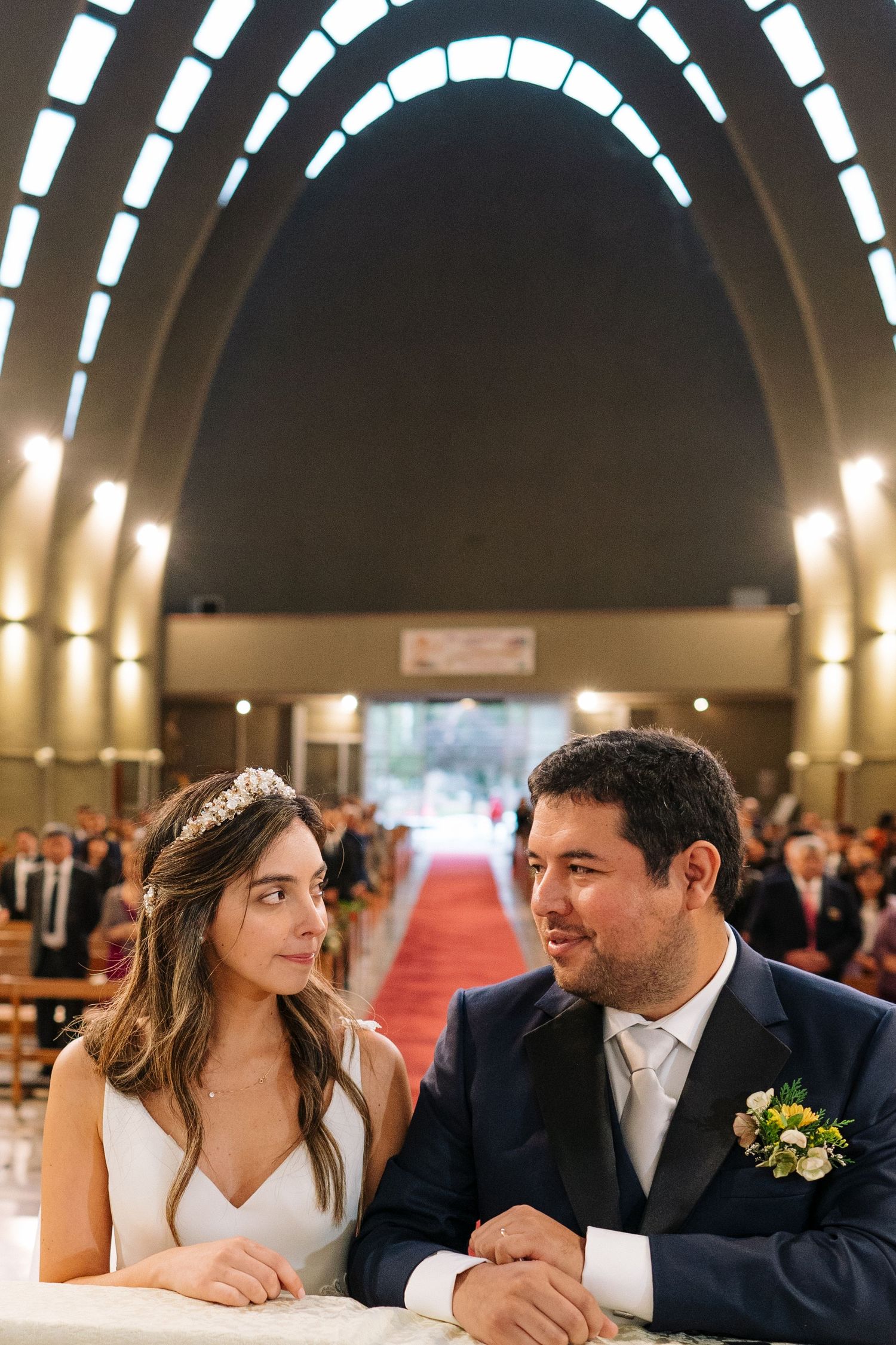 Newlyweds share intimate moment in church with dramatic arched ceiling and lighting.