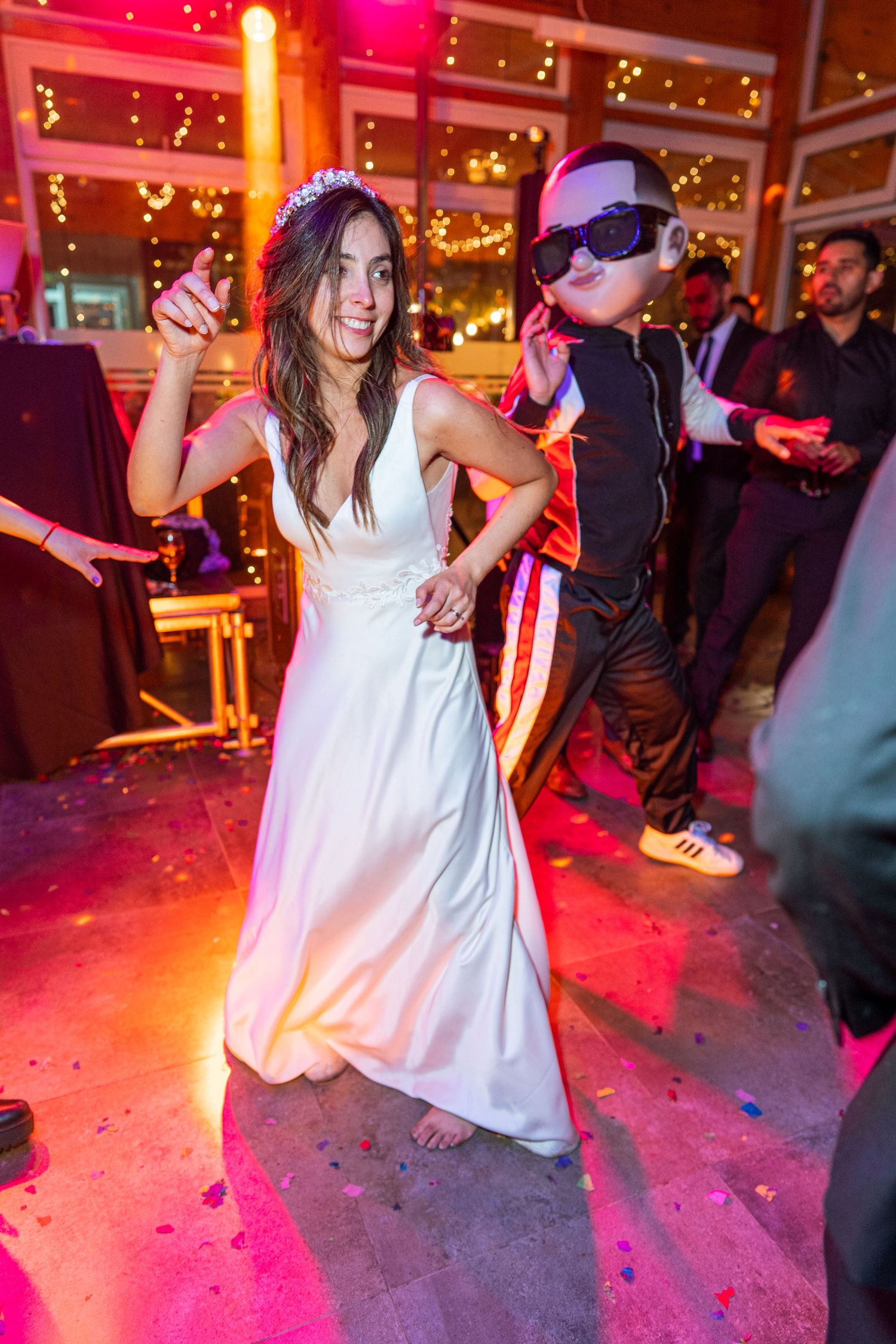 People dancing under disco lights at a celebration with colorful lighting and festive atmosphere.