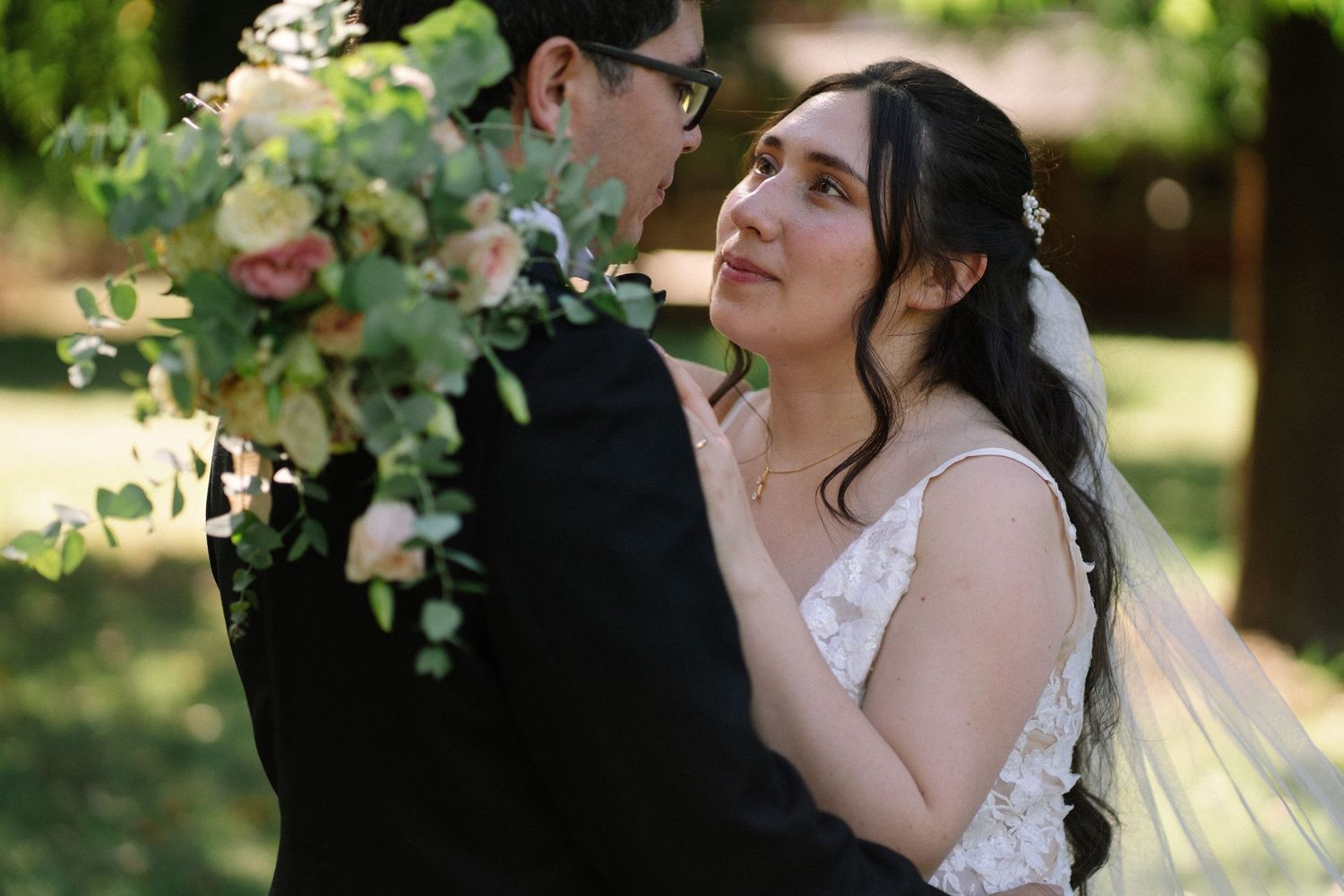 A romantic wedding portrait showing a tender moment between newlyweds among blooming garden flowers.