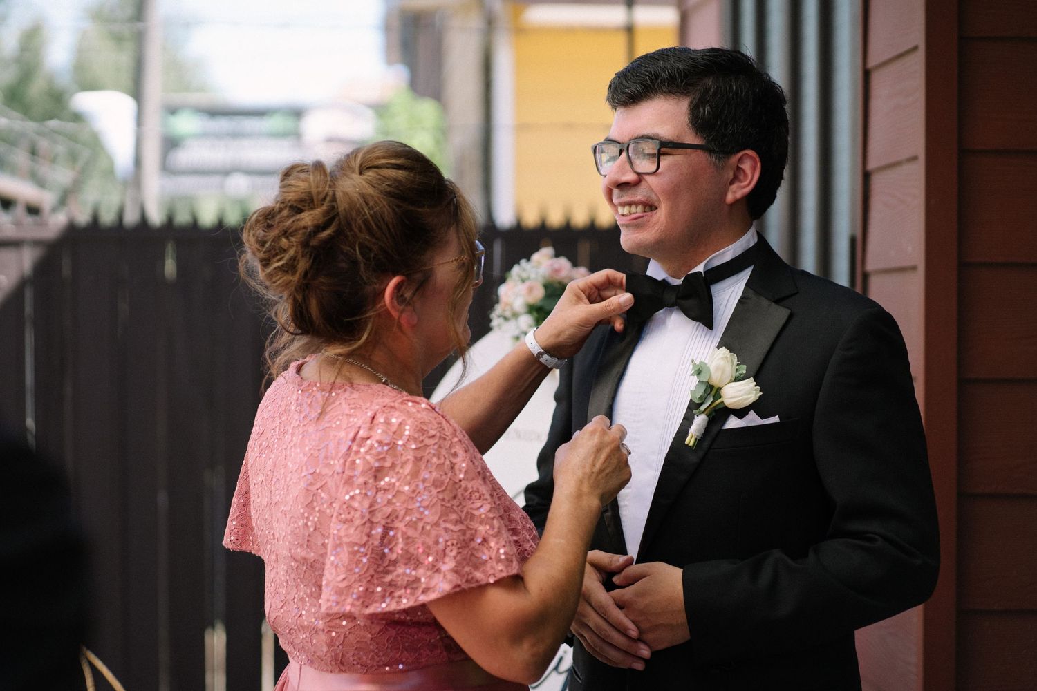 Mother helps adjust groom's bow tie in touching pre-ceremony moment.