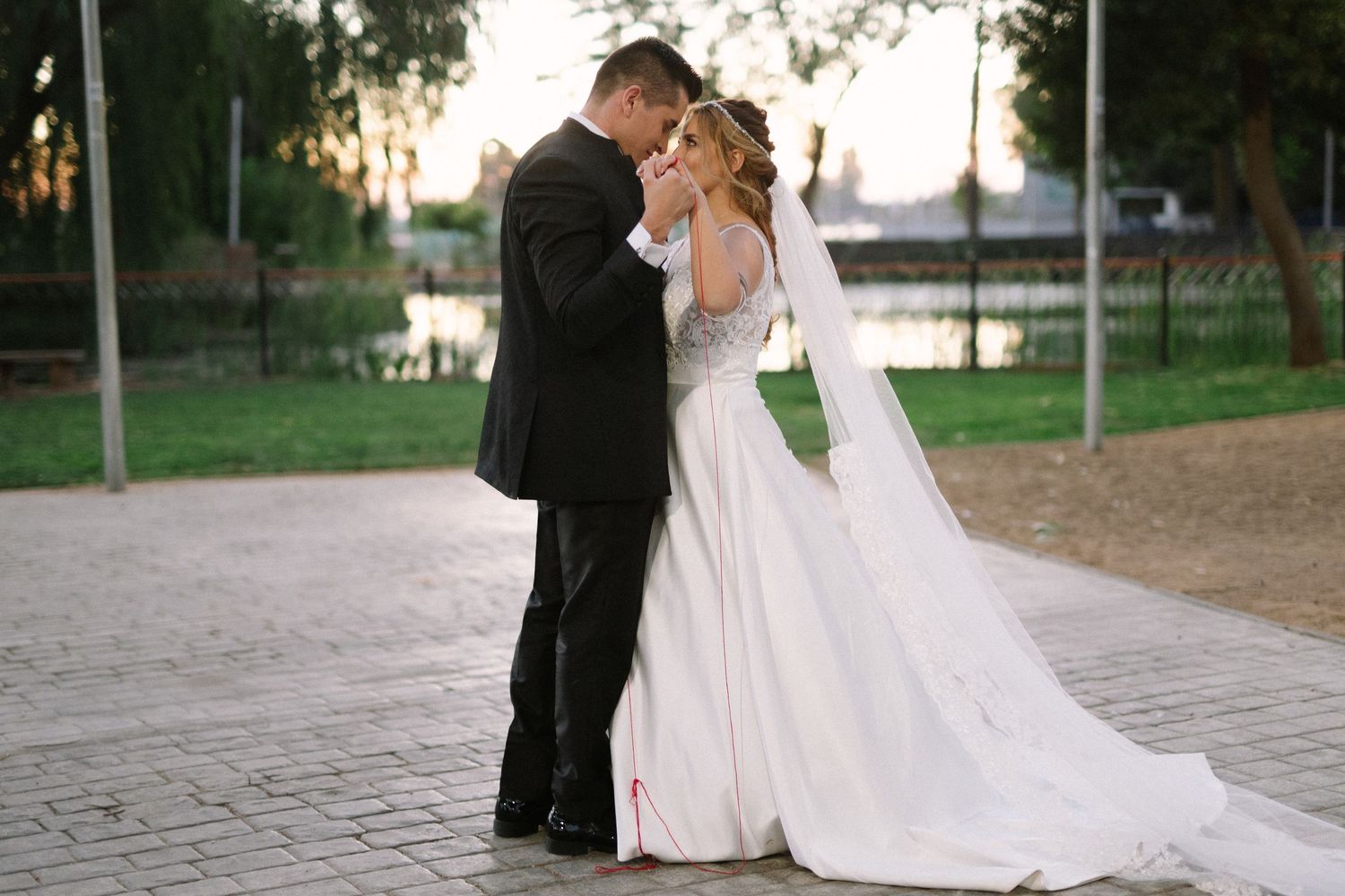 A romantic wedding couple embraces on a stone pathway at dusk.