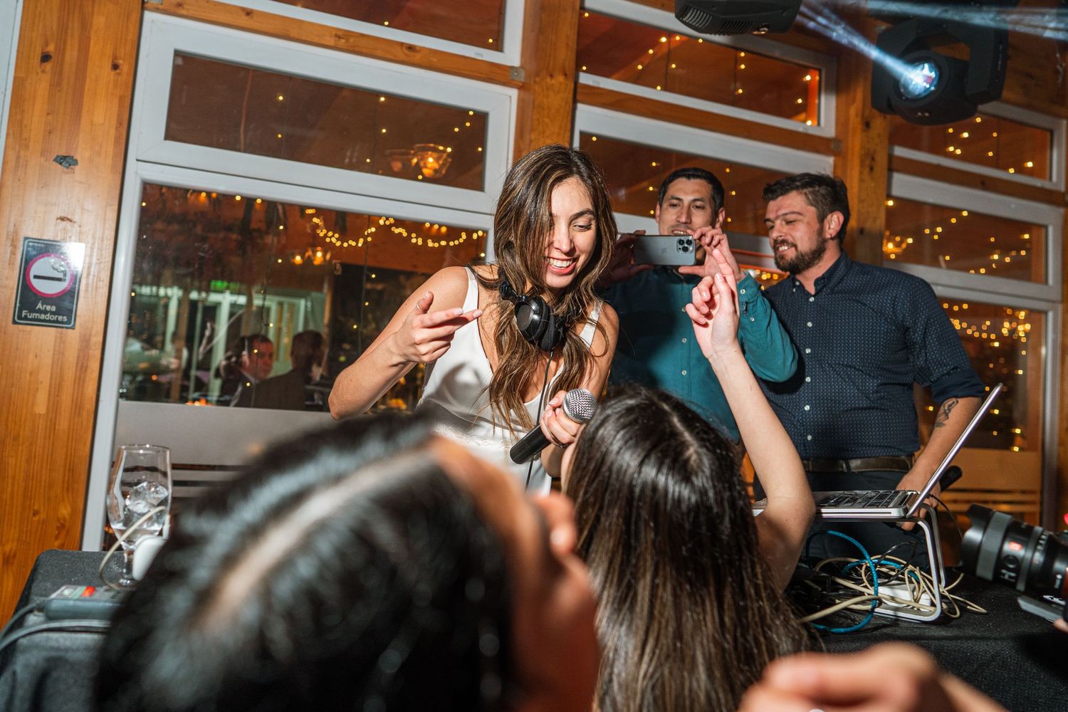 Lively celebration at a DJ booth with people dancing under warm lighting.