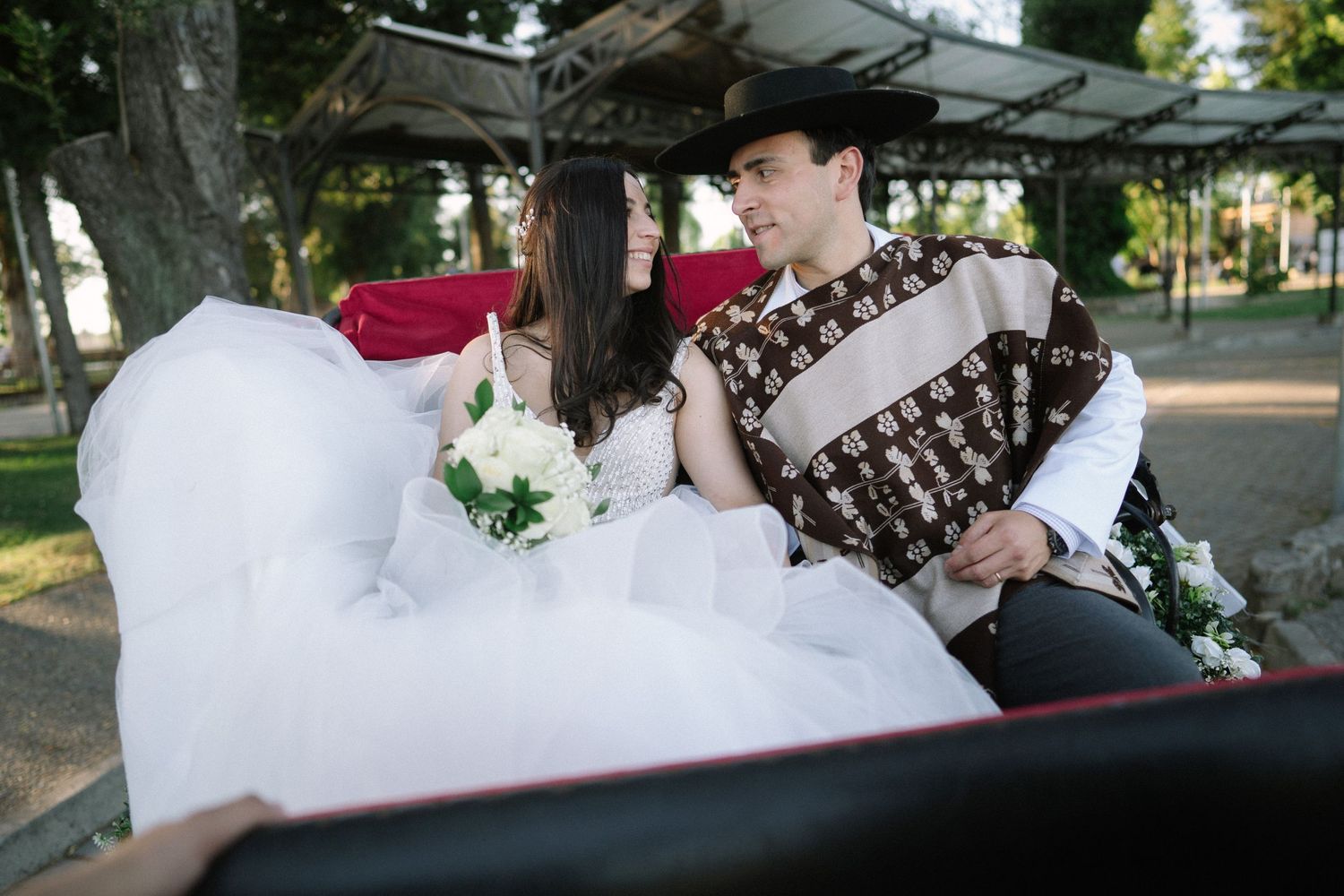 A couple shares a tender moment while seated in a vintage carriage during their wedding day.