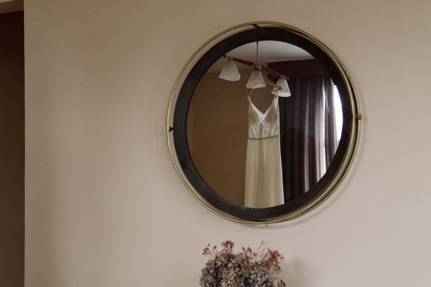 Three oval-framed mirrors hang on a beige wall above white furniture, creating an elegant vintage-inspired display.