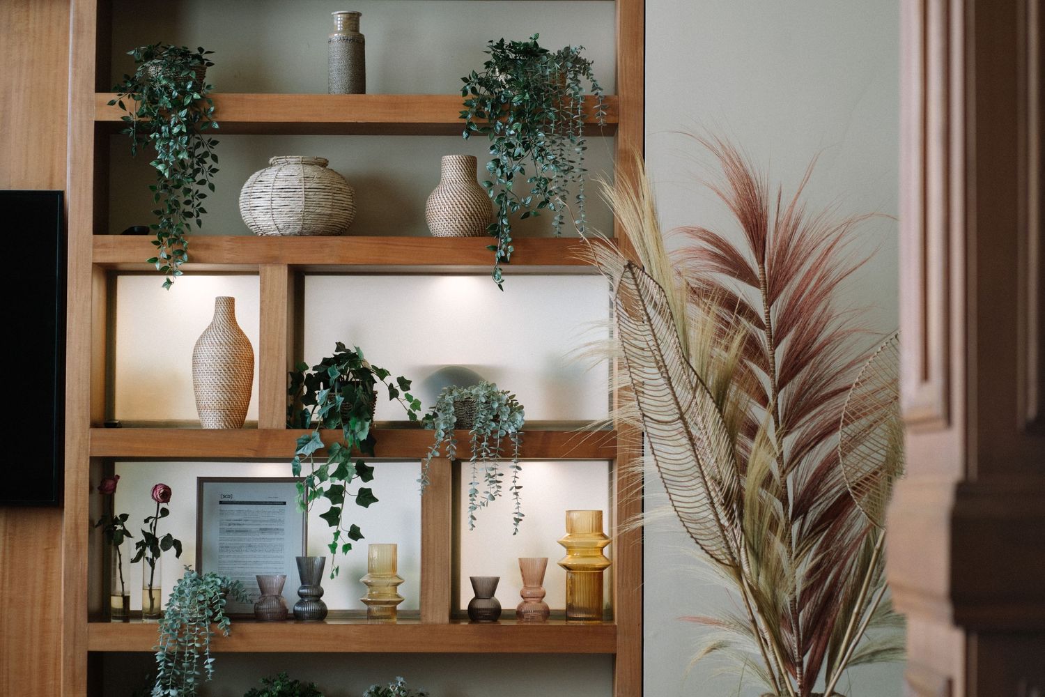 Decorative wooden shelving unit with plants, vases, and trailing ivy.