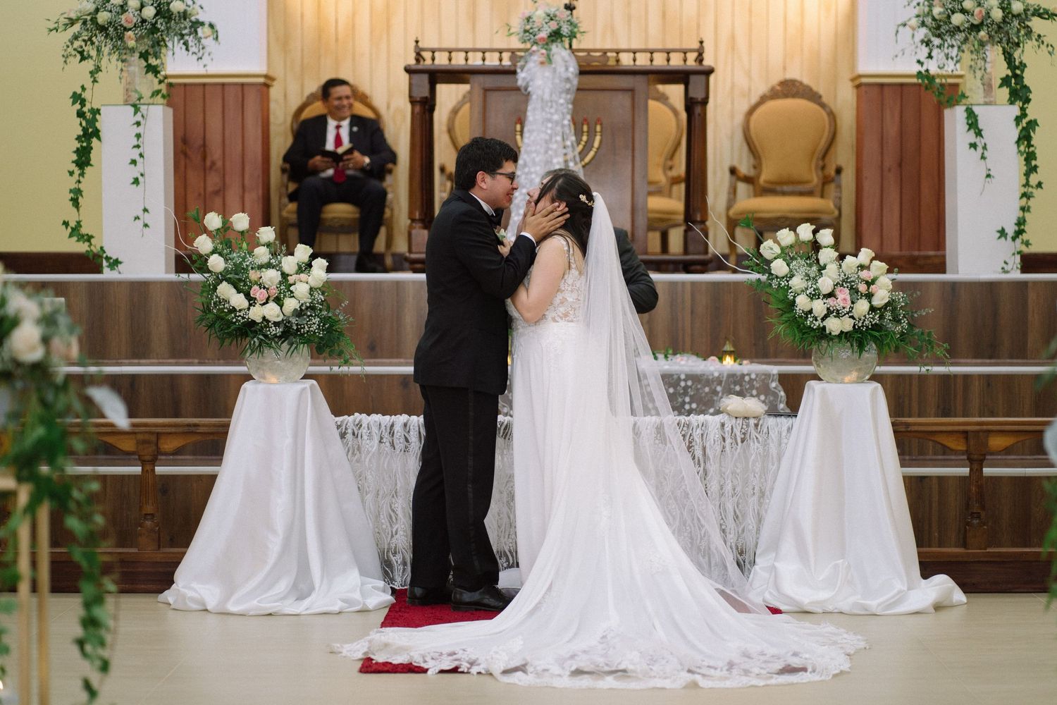 An intimate wedding ceremony moment captured at a beautifully decorated church altar.