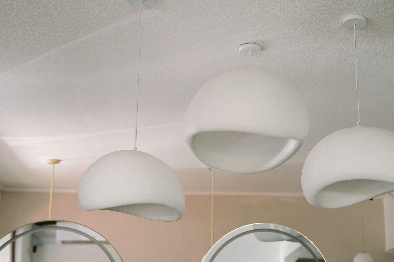 Modern white dome pendant lights hanging from a ceiling in a minimalist space.