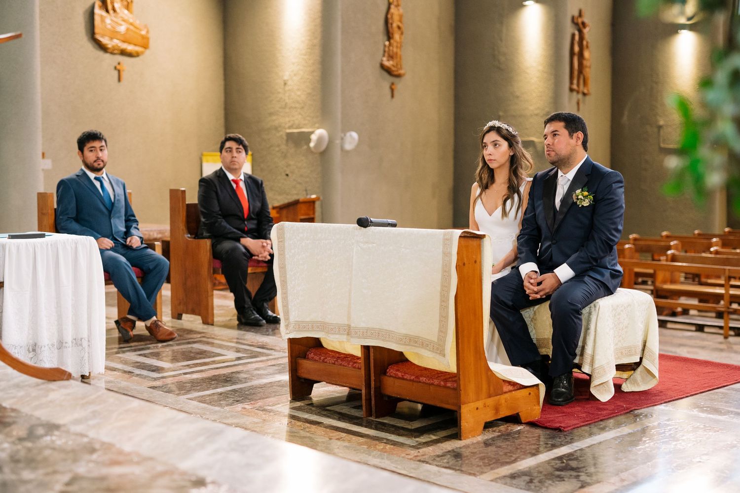 Wedding ceremony participants seated in church pews during the service.