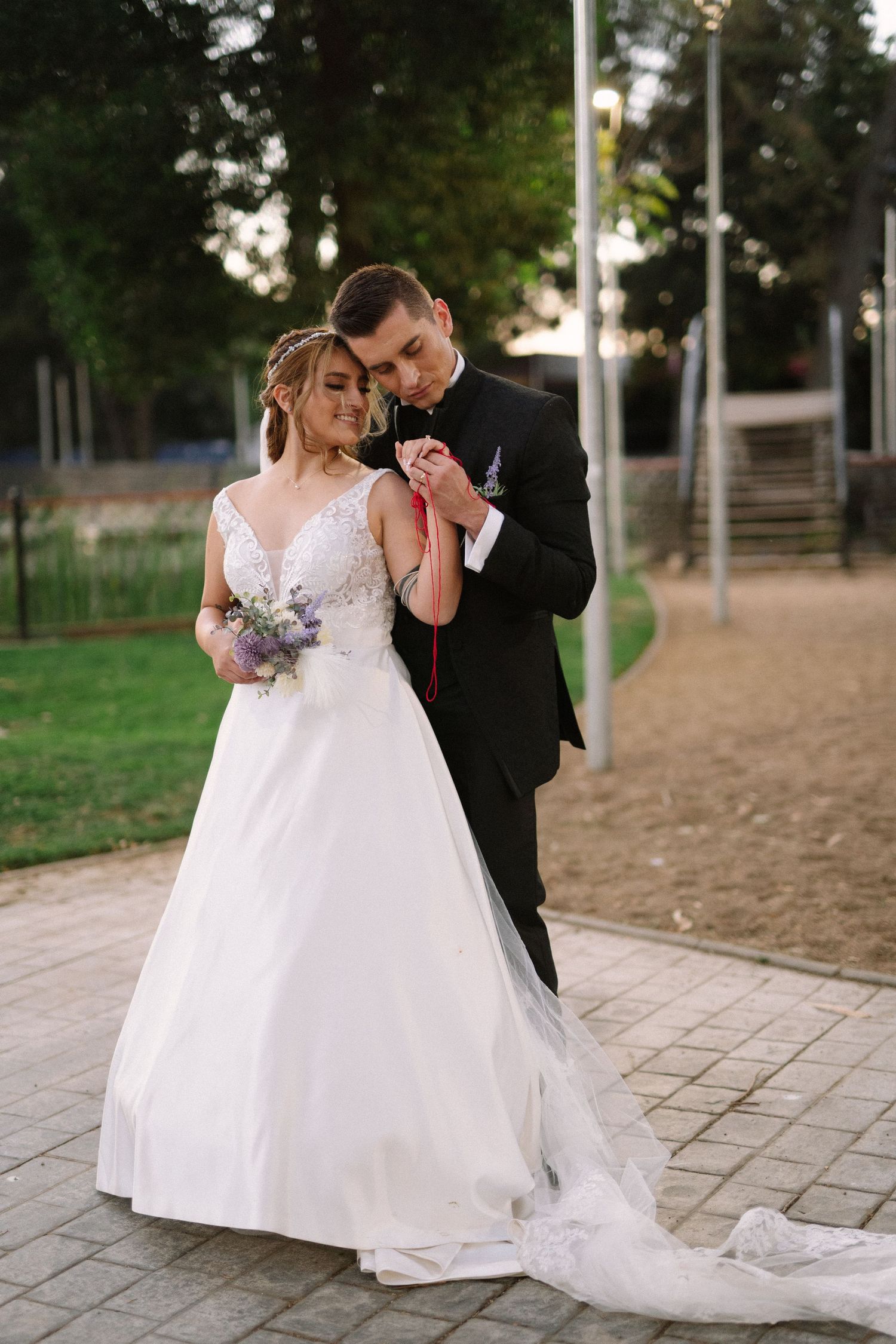 A couple in wedding attire shares a tender dance moment outdoors at sunset.