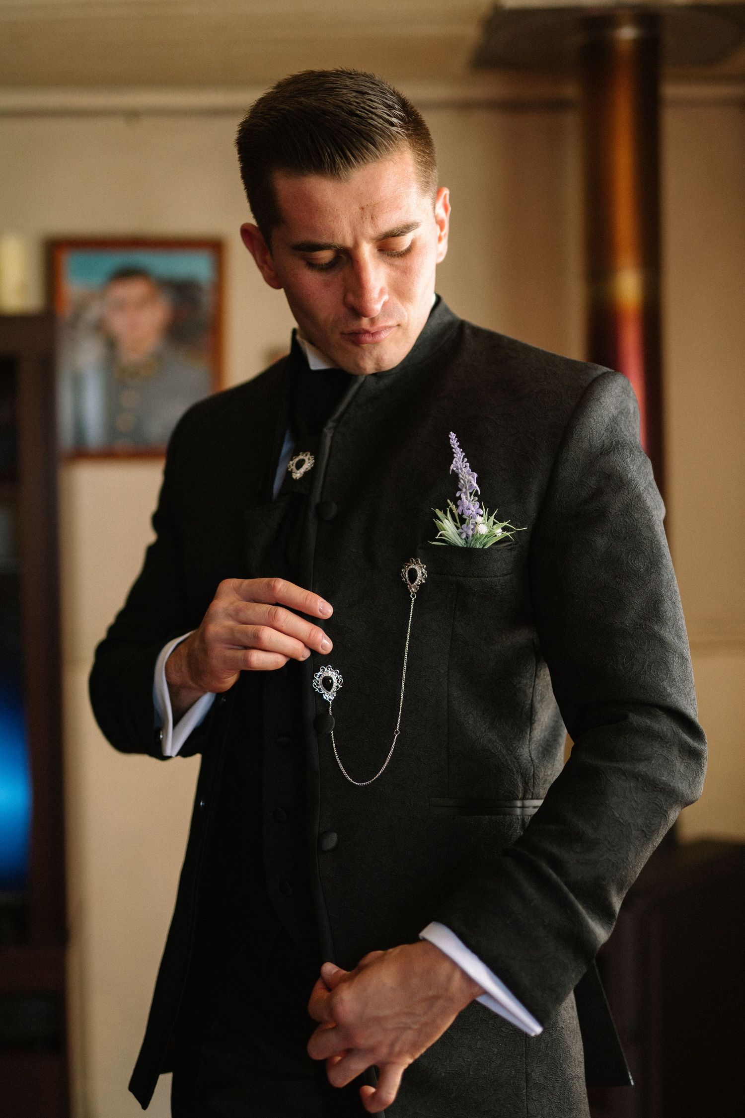 Person in black formal suit with boutonniere and pocket watch chain.