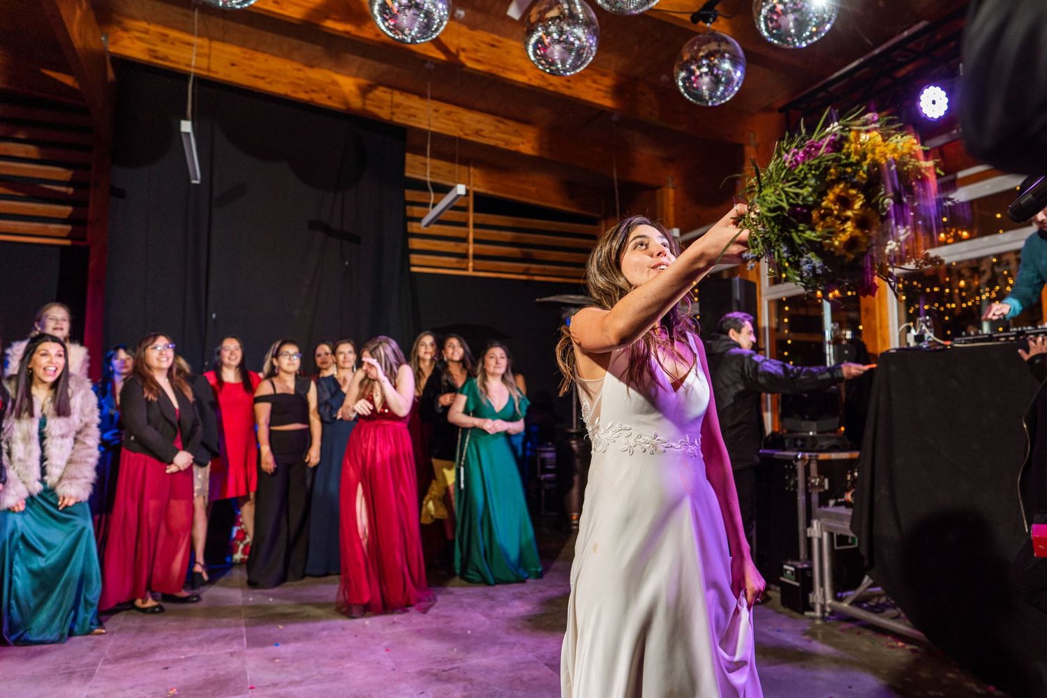 Wedding celebration with bouquet toss in front of crowd wearing formal attire.