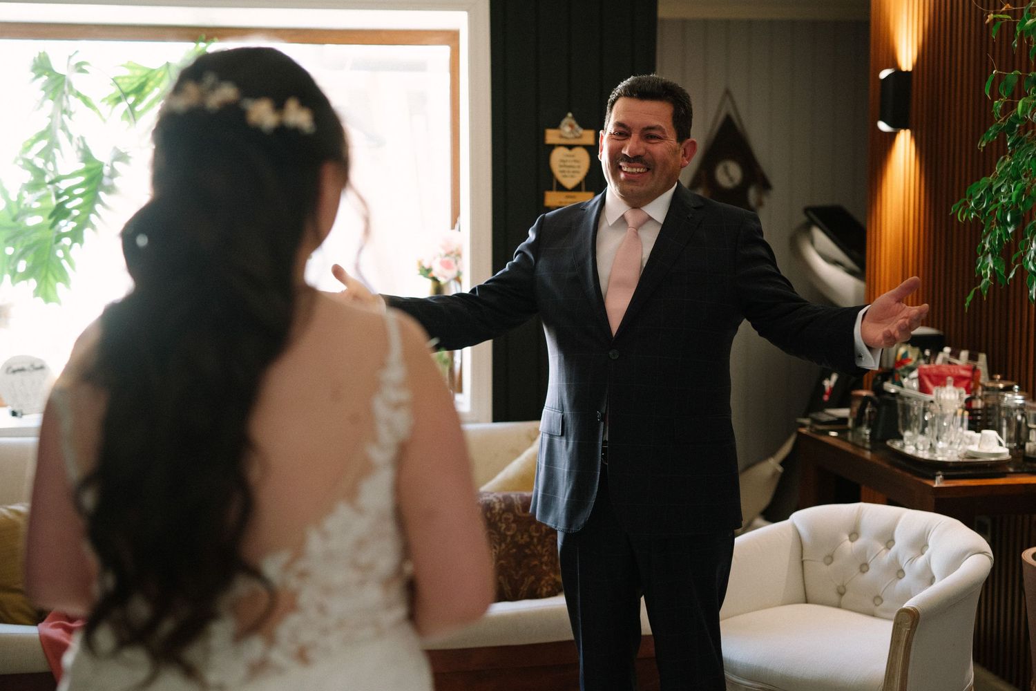 Emotional first look moment between bride and groom in living room setting.