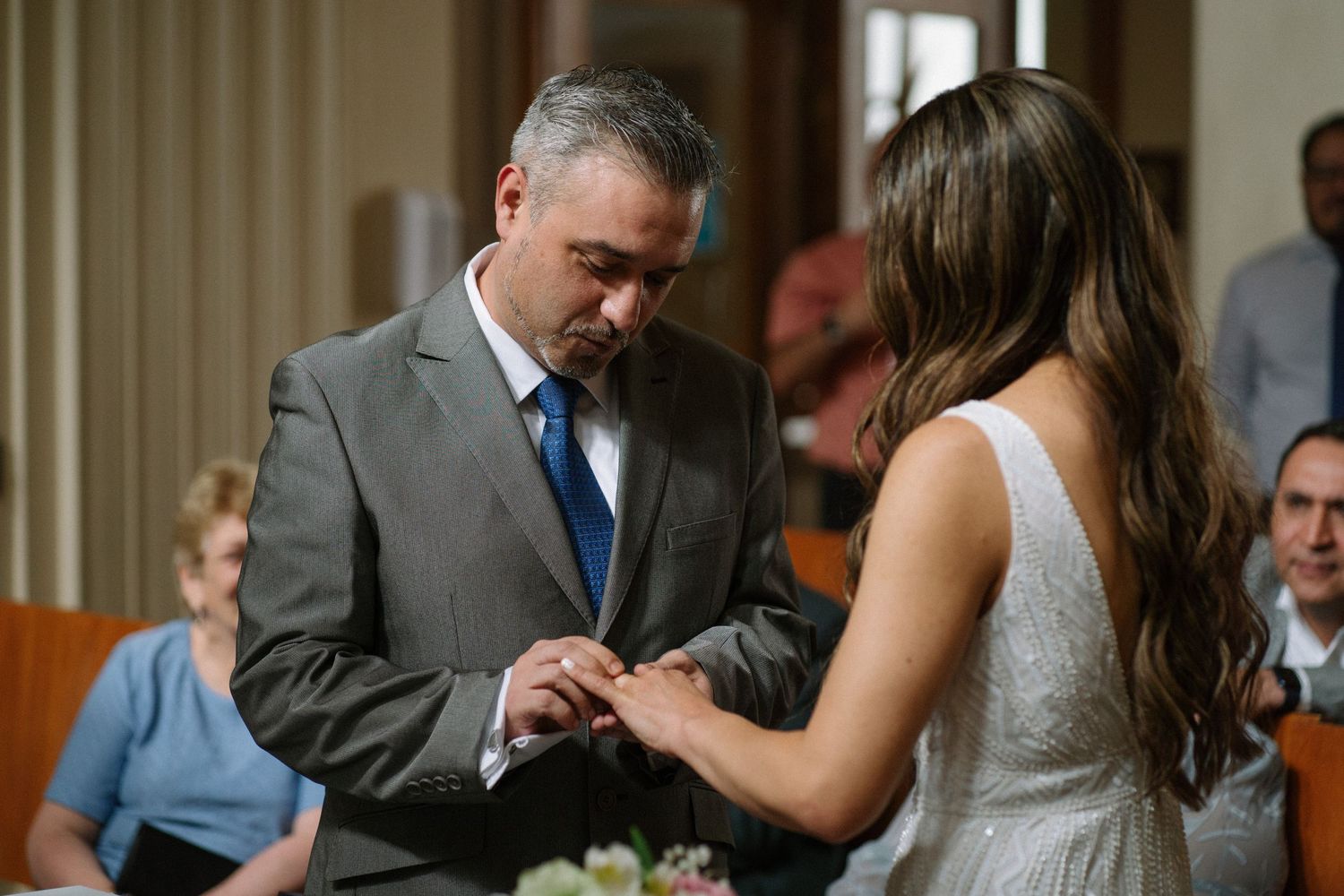 Couple exchanges rings during an intimate wedding ceremony indoors.