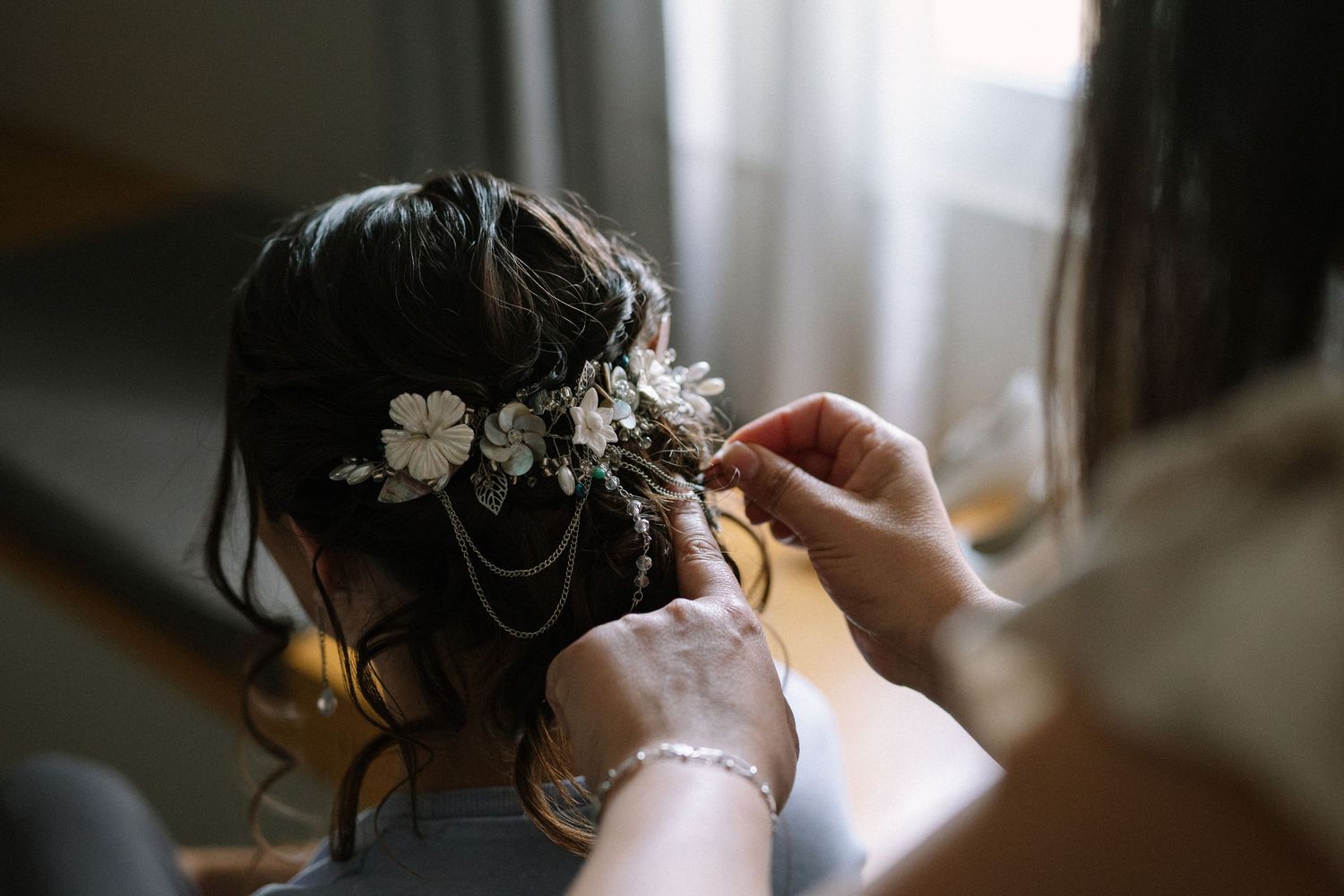 Delicate floral hair accessories being pinned into an elegant bridal hairstyle.