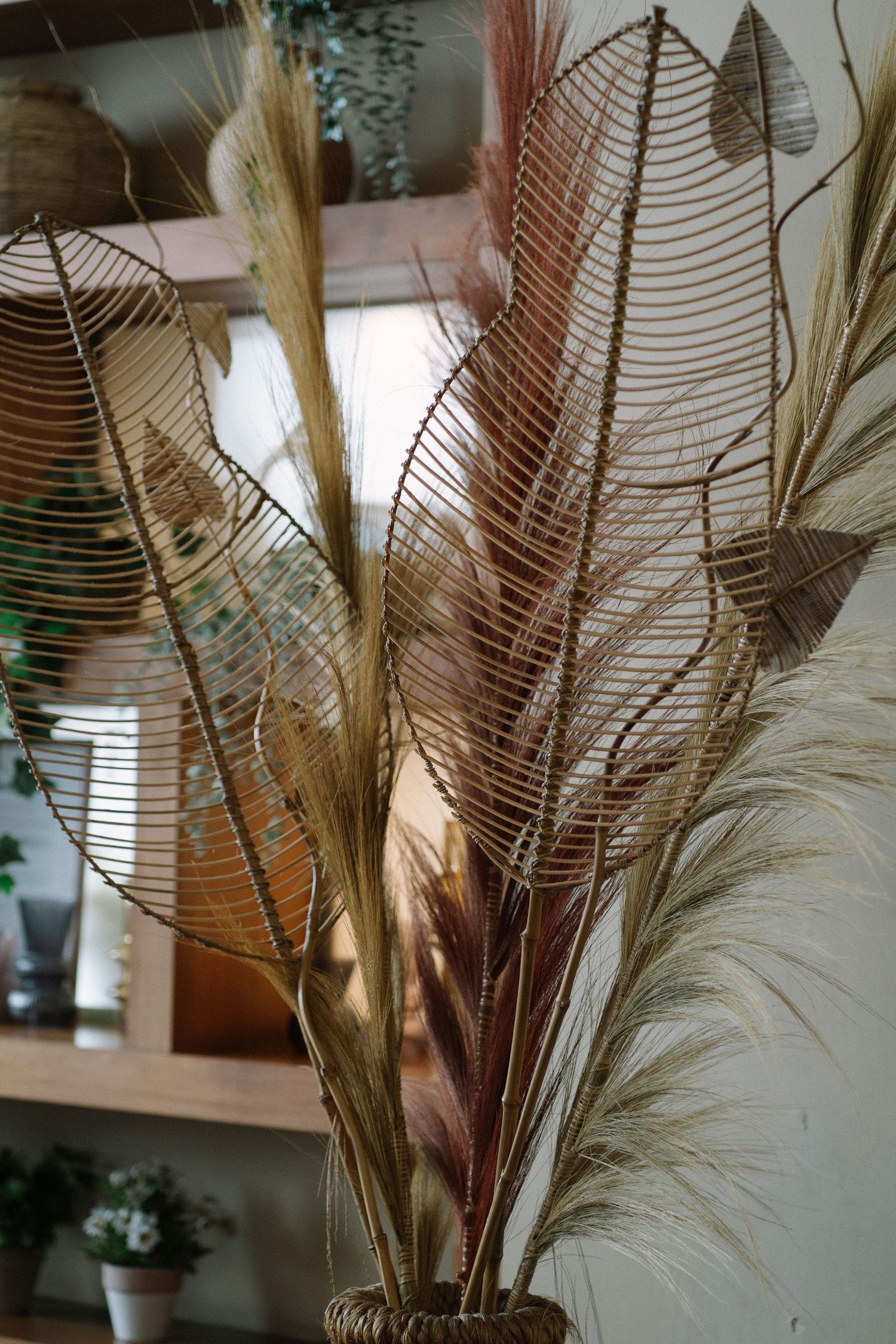 Decorative arrangement of dried pampas grass and wire leaf sculptures.