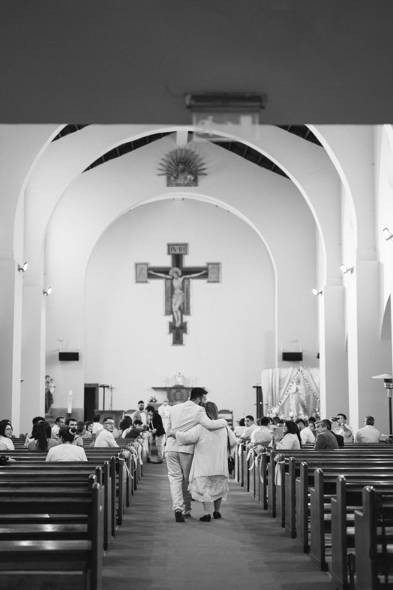 Church interior with arched ceiling and crucifix during a ceremony.