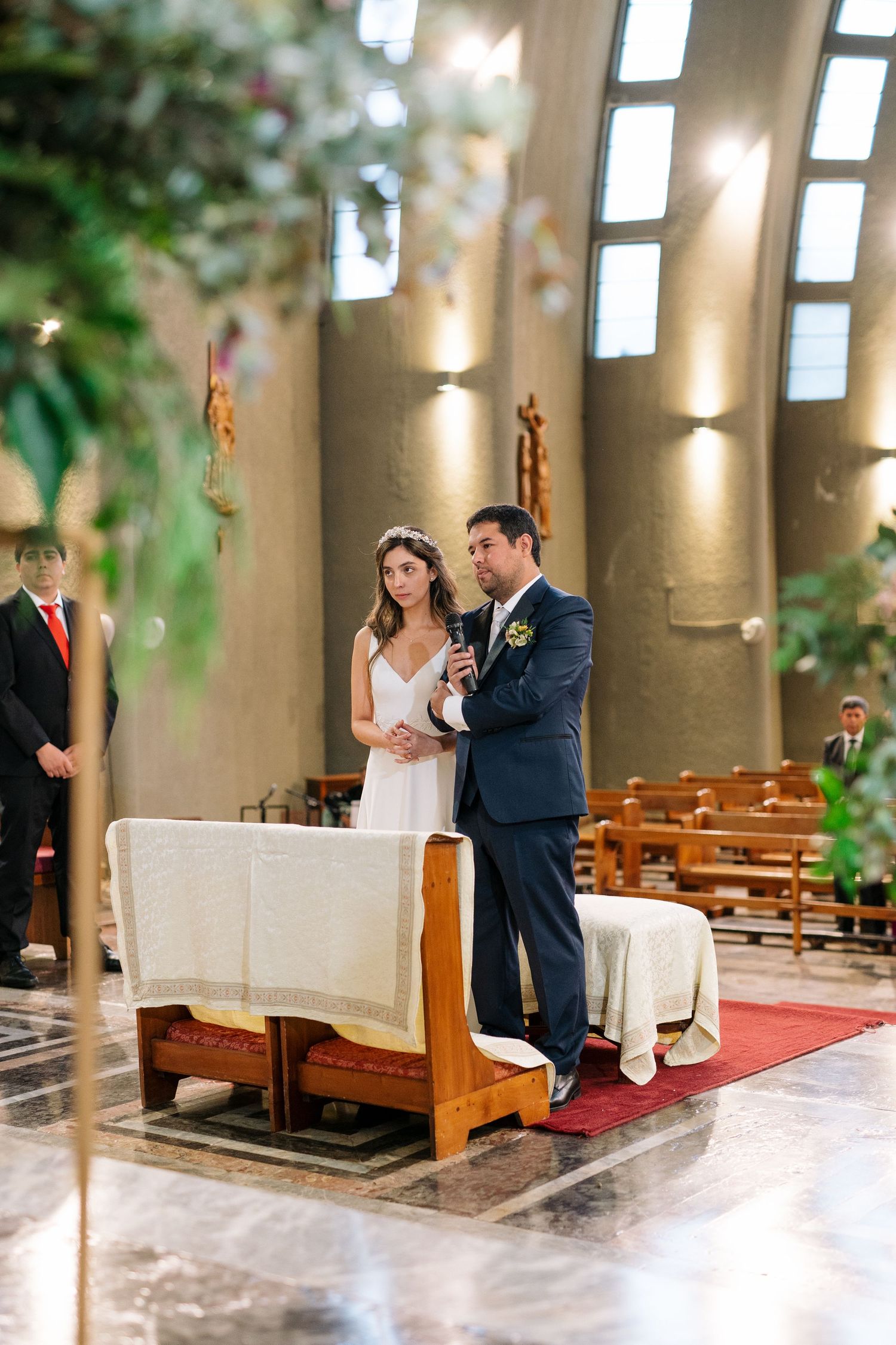 A wedding ceremony taking place in a modern church with dramatic natural lighting.