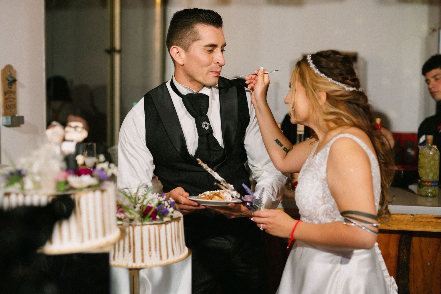 Newlyweds playfully feed each other cake during their wedding reception celebration.