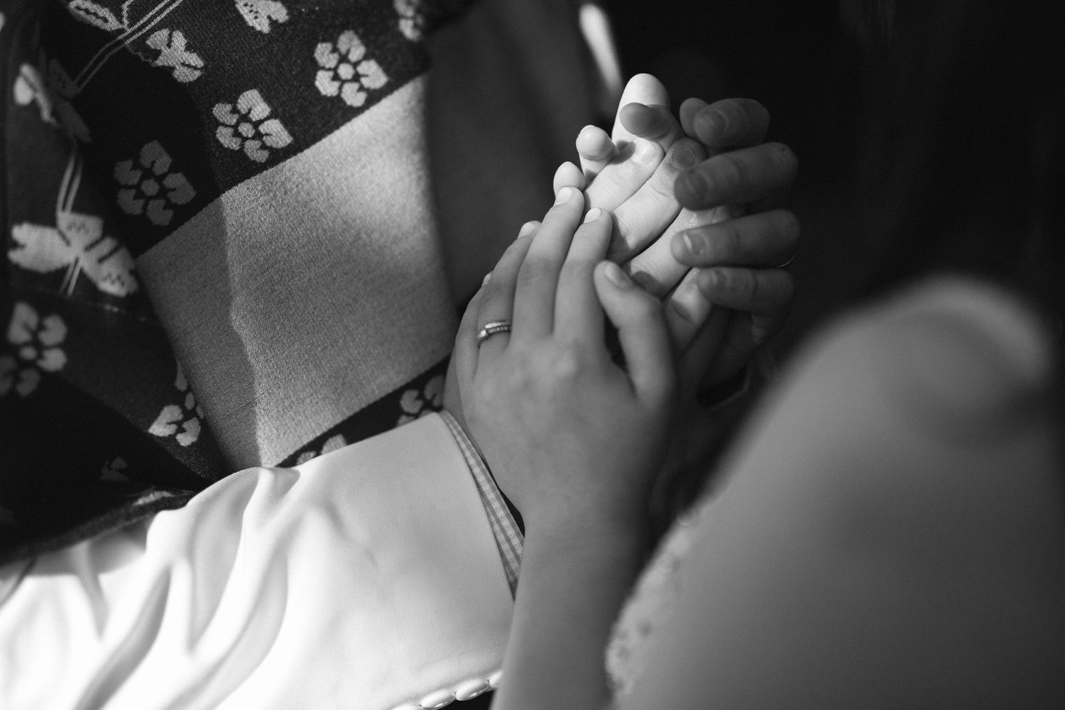 Close-up black and white photo of hands clasped together during ceremony.