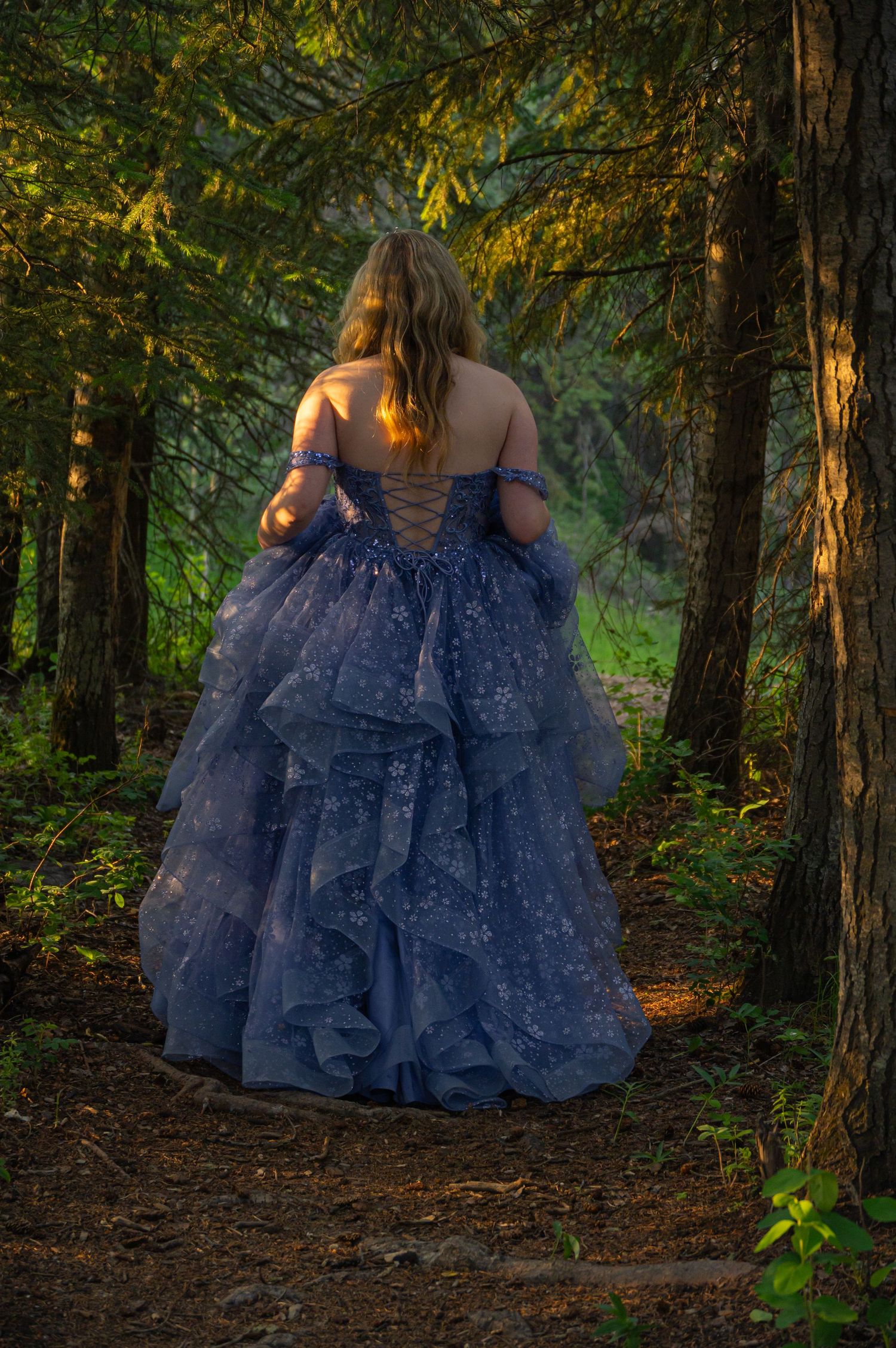 A flowing blue tulle ball gown photographed from different angles in a mystical forest setting during golden hour.
