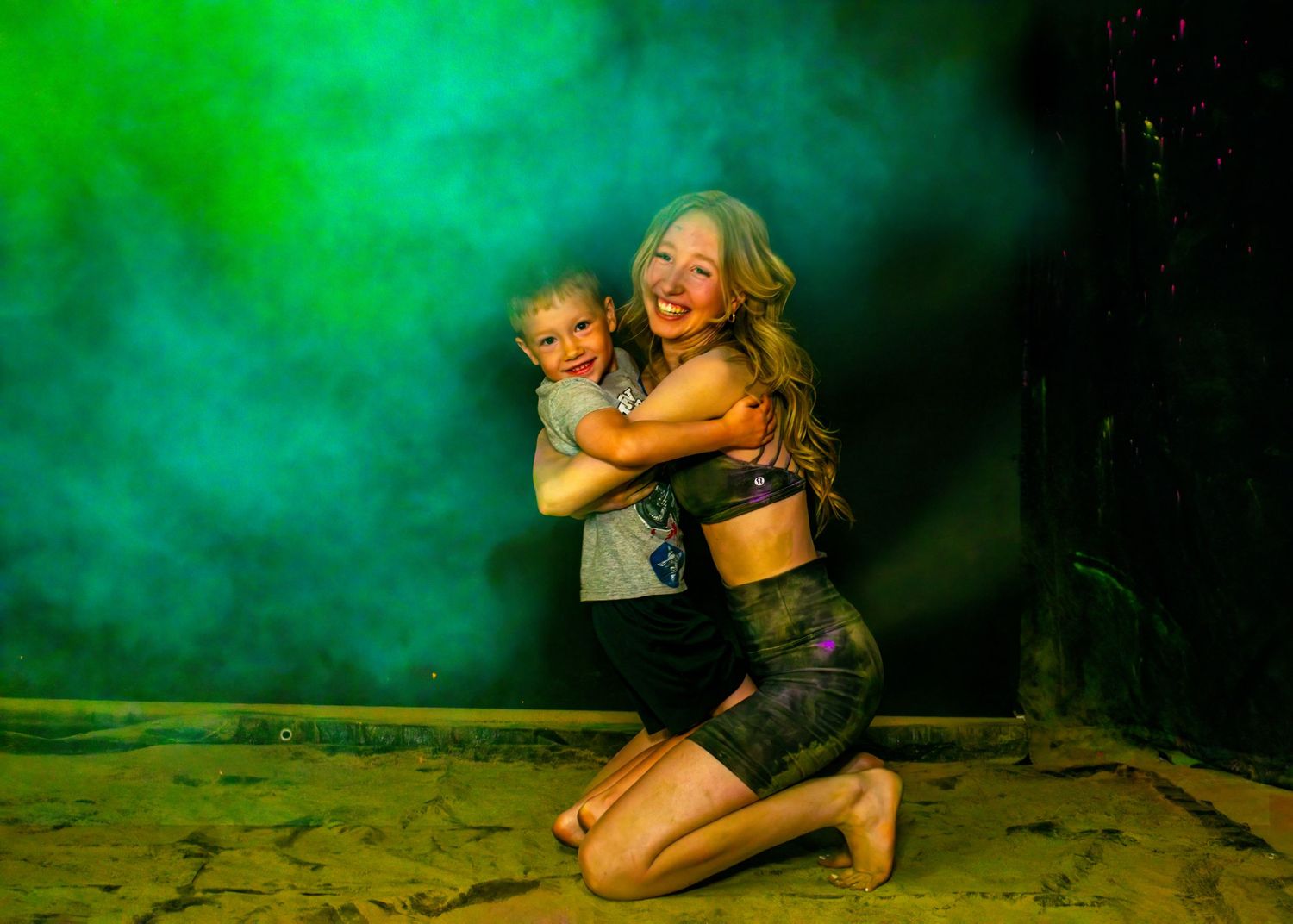 Dance portrait with green smoke effects capturing tender moment against dark backdrop.