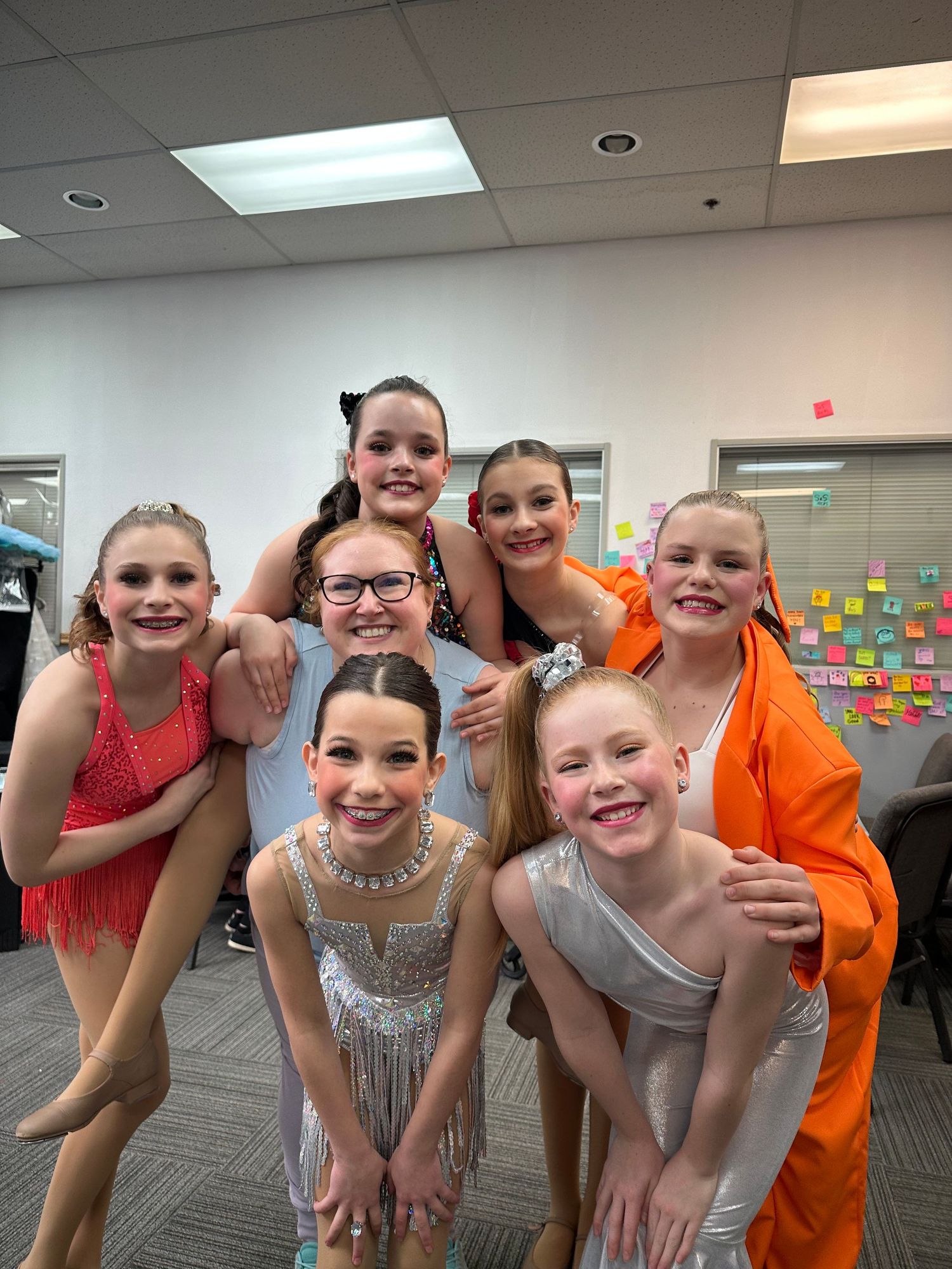Group of dancers in colorful performance costumes posing together backstage.