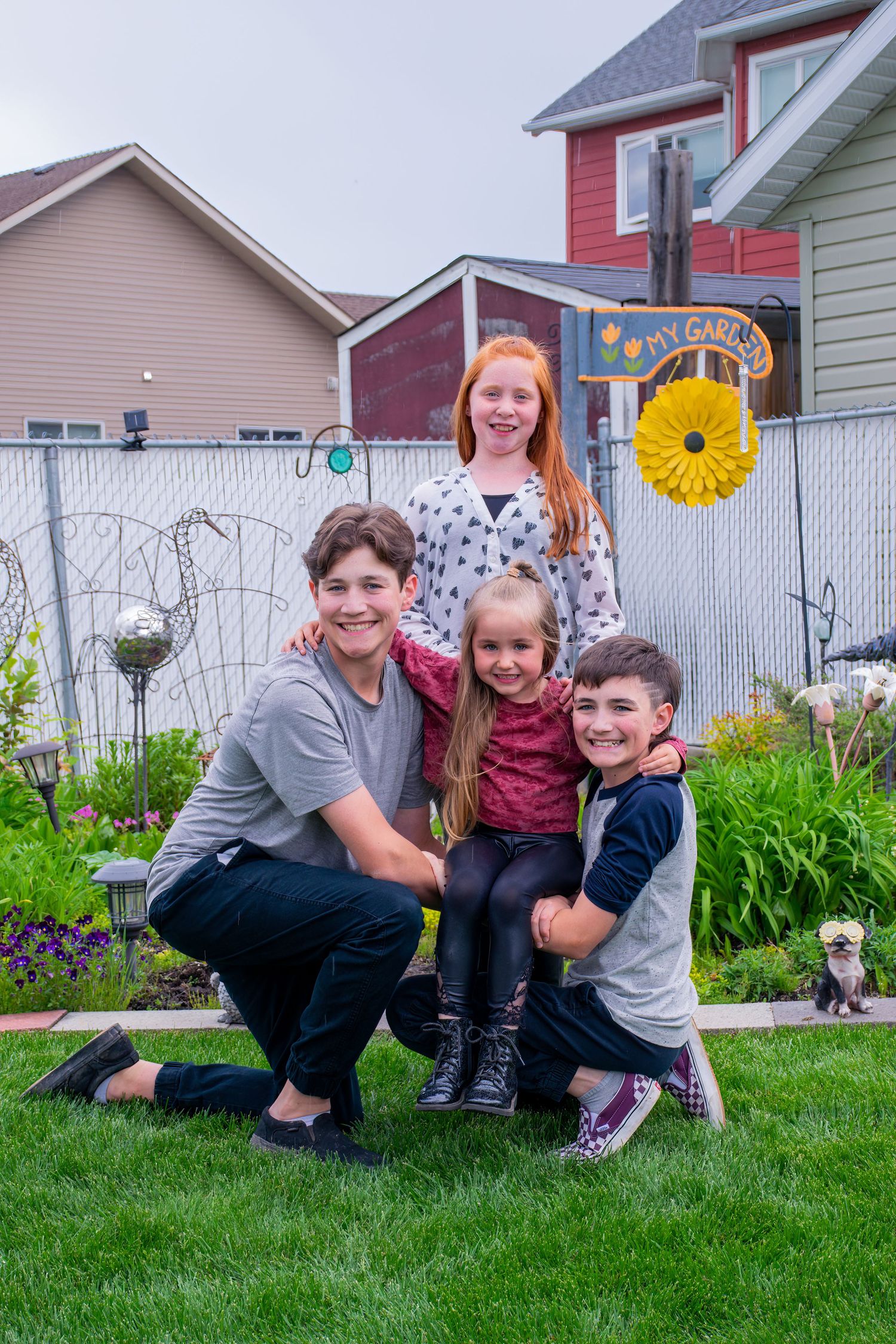 Group portrait of family members posing together in a backyard garden with colorful decorations.