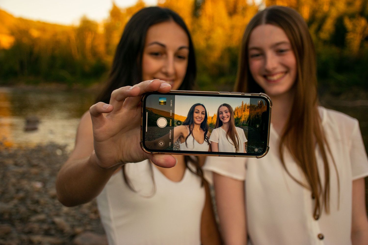 Two friends taking a selfie together outdoors during golden hour.