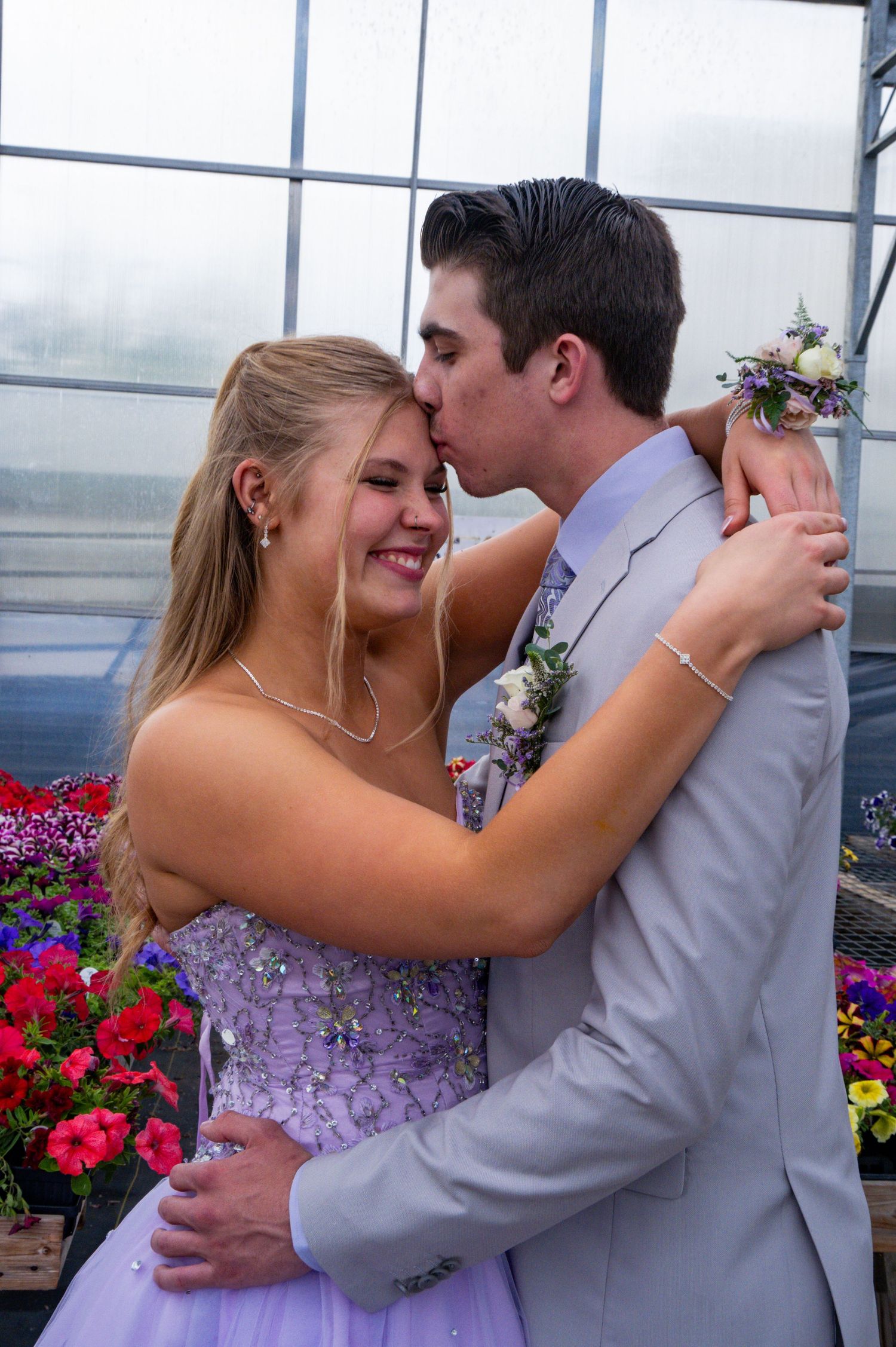 A romantic wedding couple embrace near colorful flowers in a bright glass-walled venue during their special day.