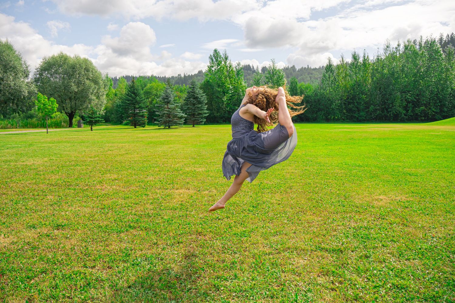 Series of acrobatic backflip movements photographed in sequence on an open field bordered by trees.
