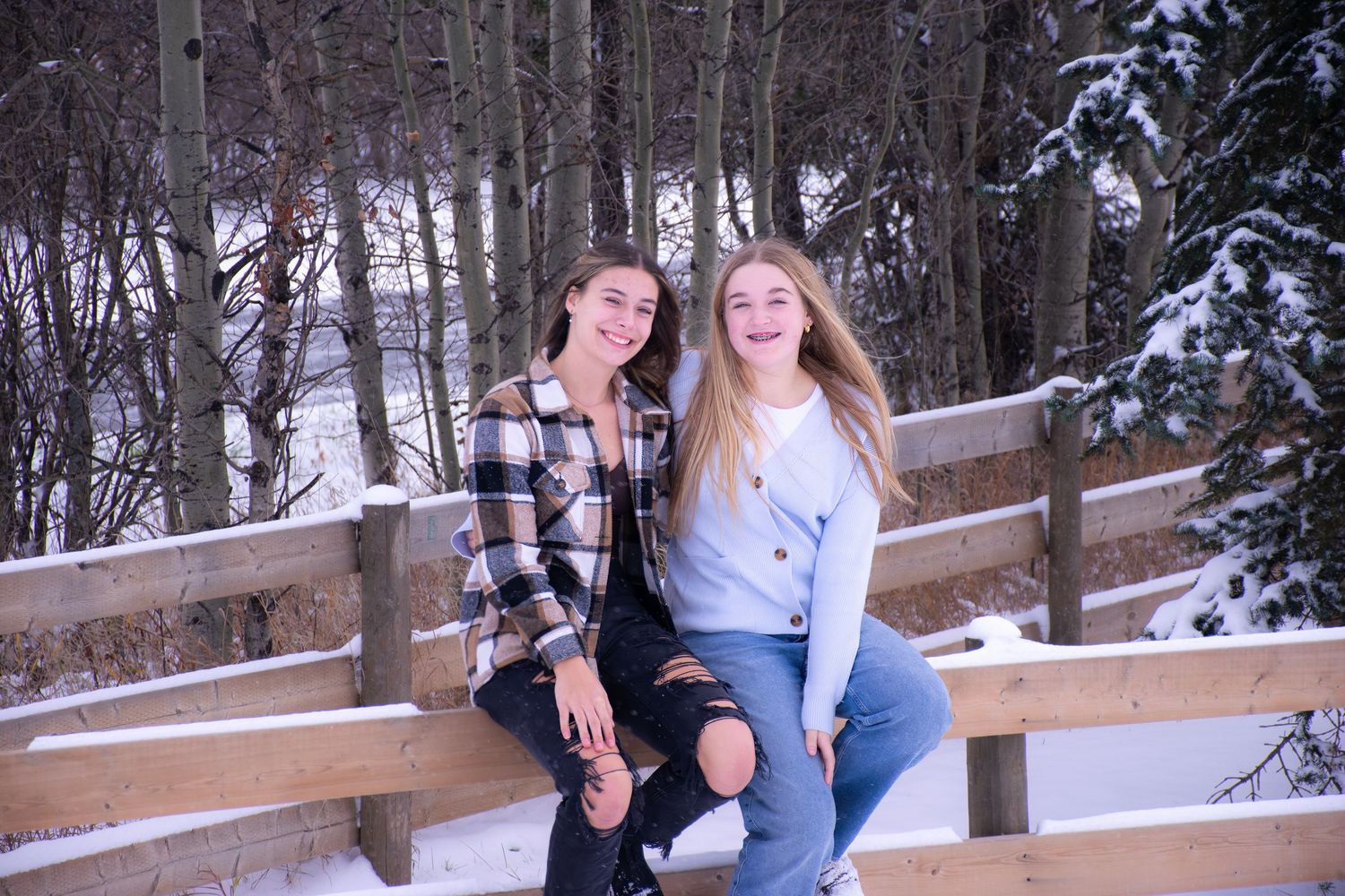 Two friends sit together on a wooden bench surrounded by snowy winter scenery.