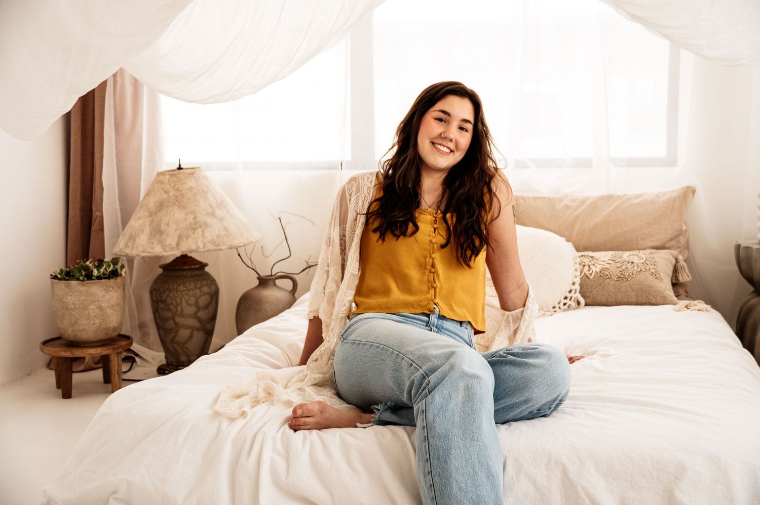 A casual lifestyle photo showing someone relaxing on a white bed with natural lighting.