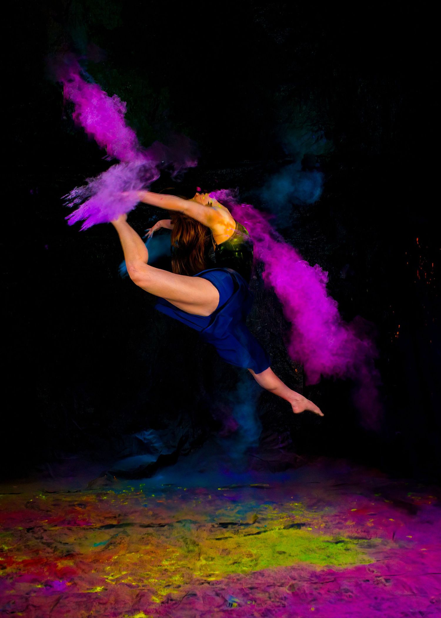 A dynamic dance photo with colorful powder effects against a black background.