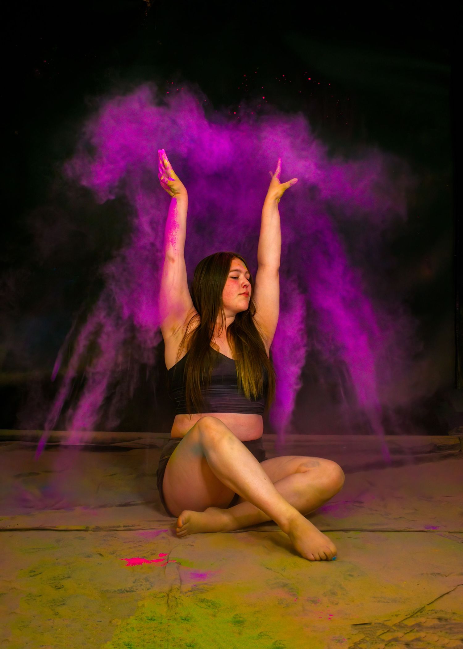 Artistic dance portrait with purple powder explosion effect against black background.