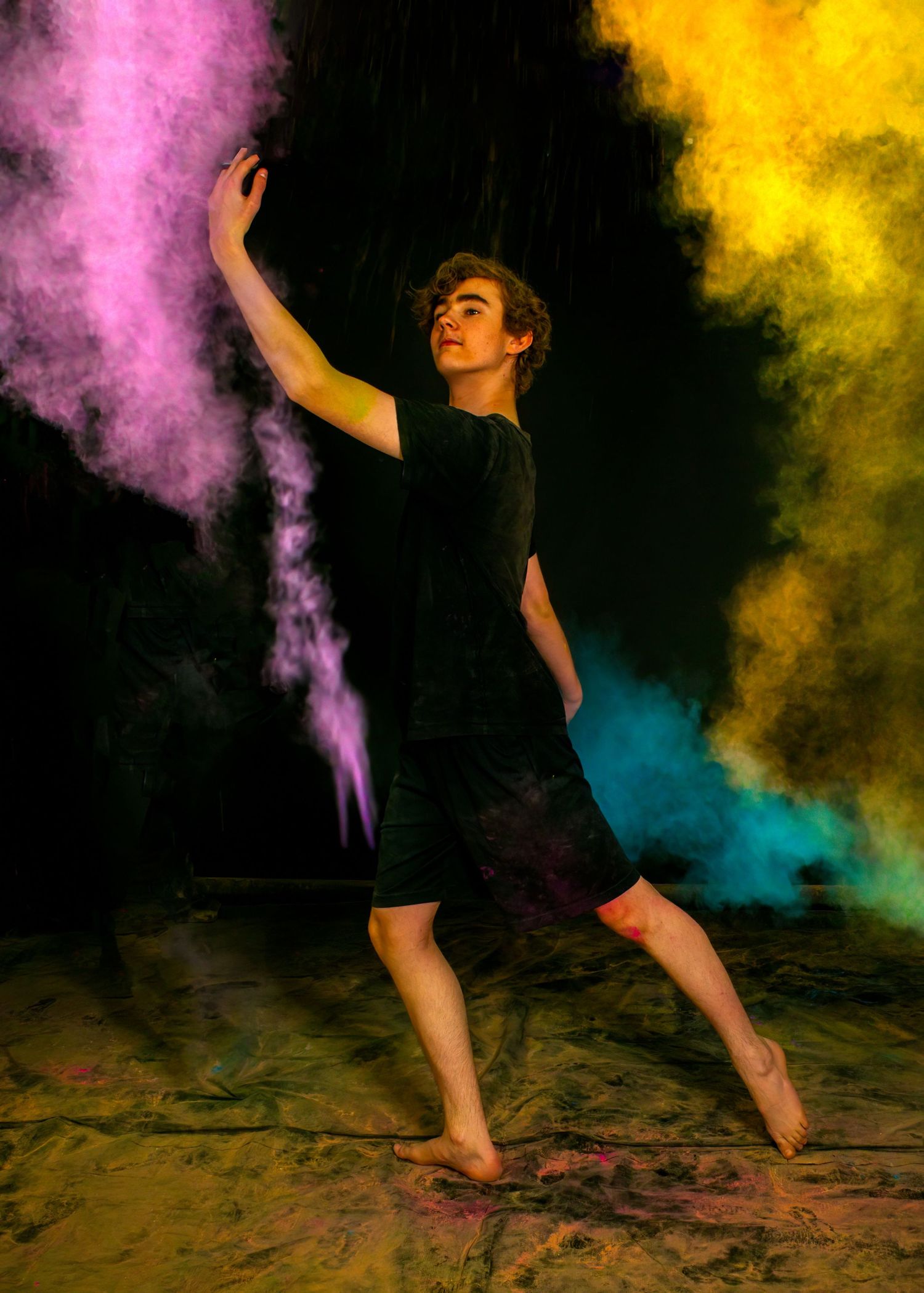 Contemporary dancer posing gracefully with pink and yellow powder effects.