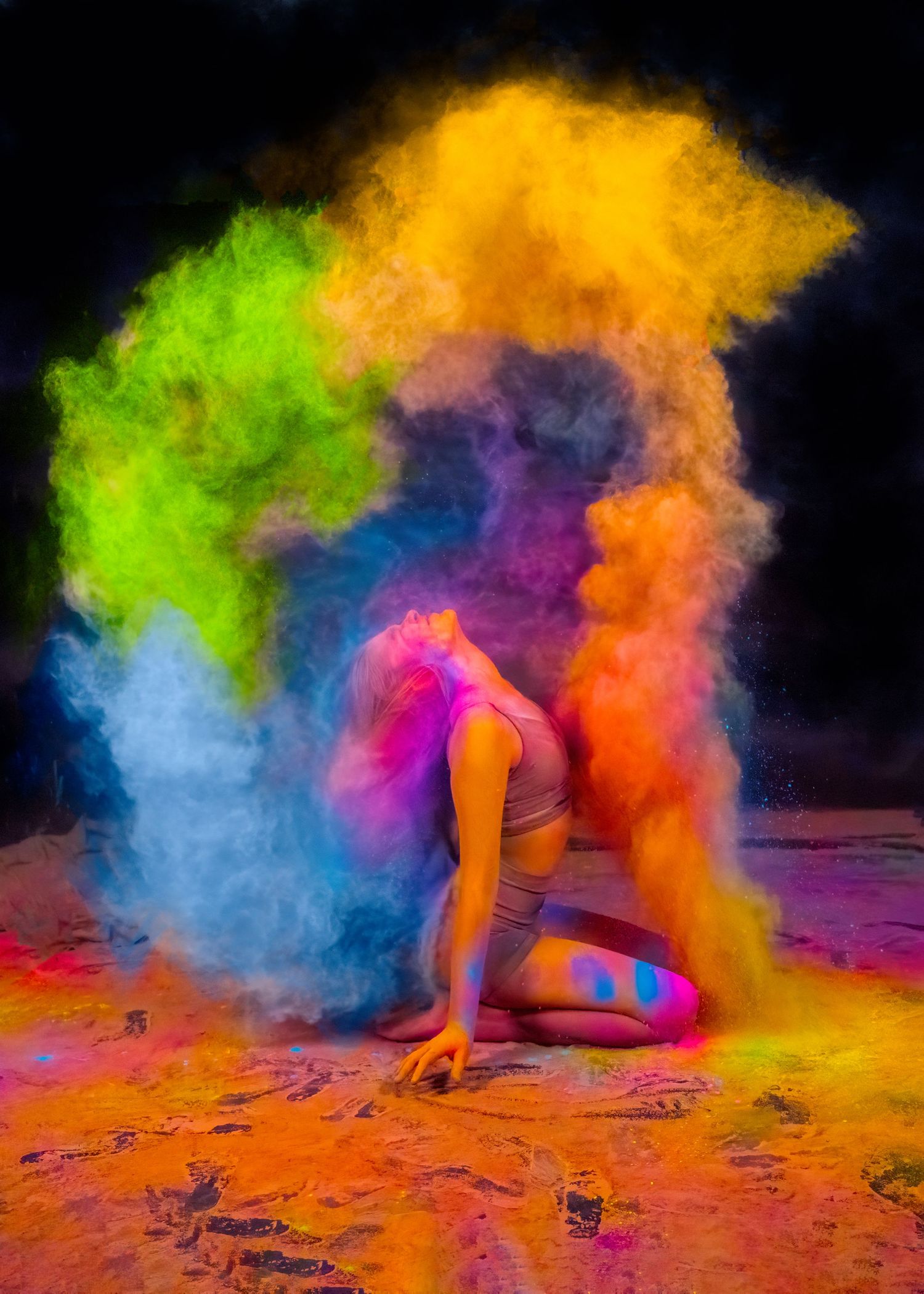 Colorful powder explosion creates rainbow effect around a dancer in dramatic pose.