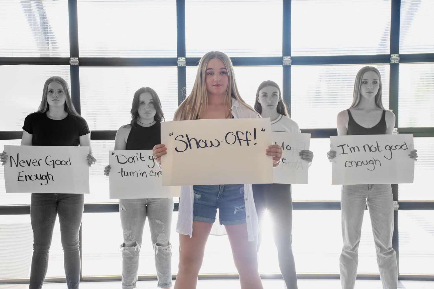 A group poses with motivational signs in a bright indoor setting.