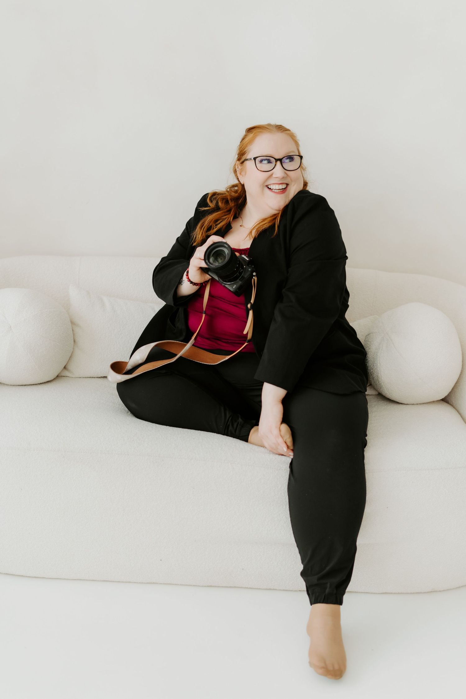 Photographer relaxing on a white couch with a camera.