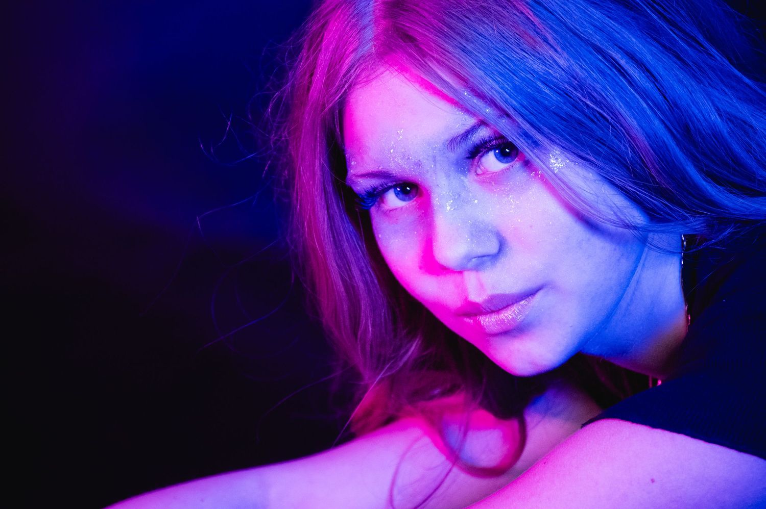 Portrait lit with vibrant pink and blue neon lighting effects.