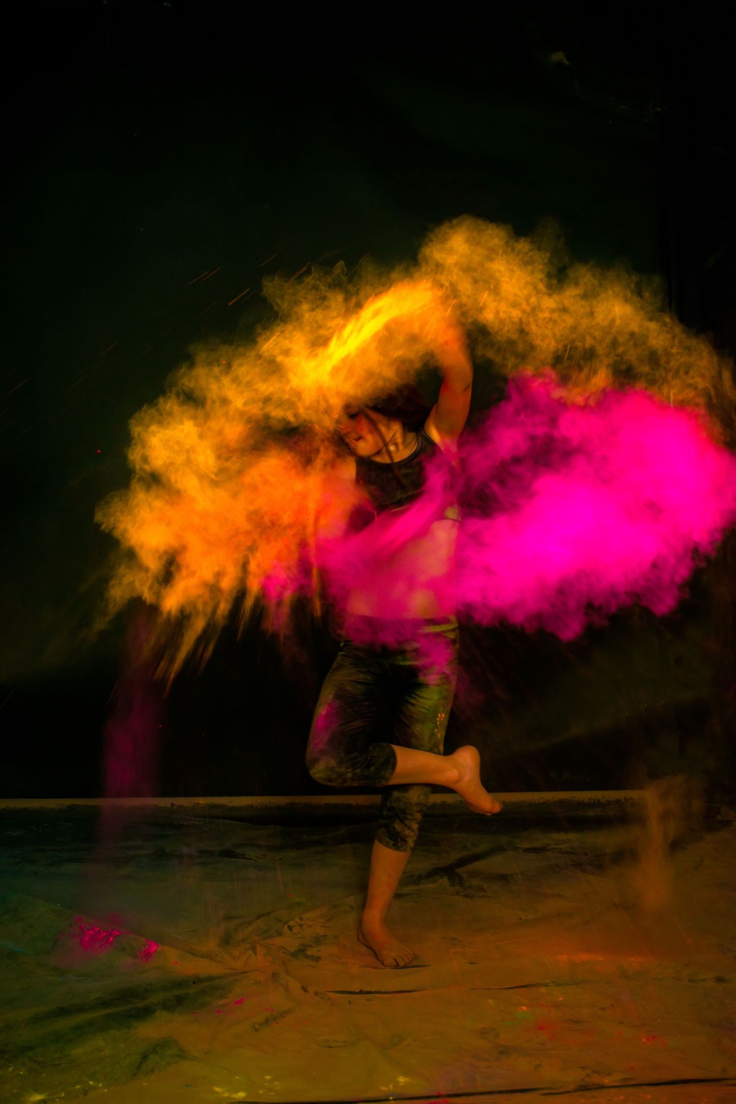 Dynamic dance movement captured with orange and pink smoke creating ethereal effect.