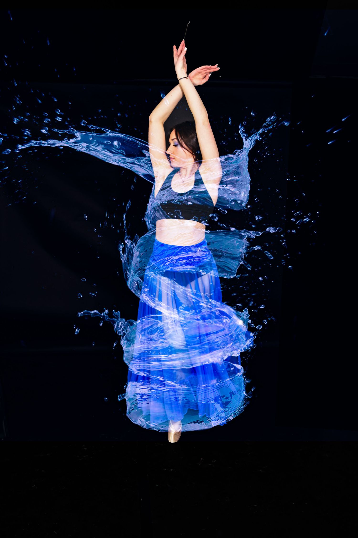 Dancer in blue dress with water effects splashing around in artistic performance shot.