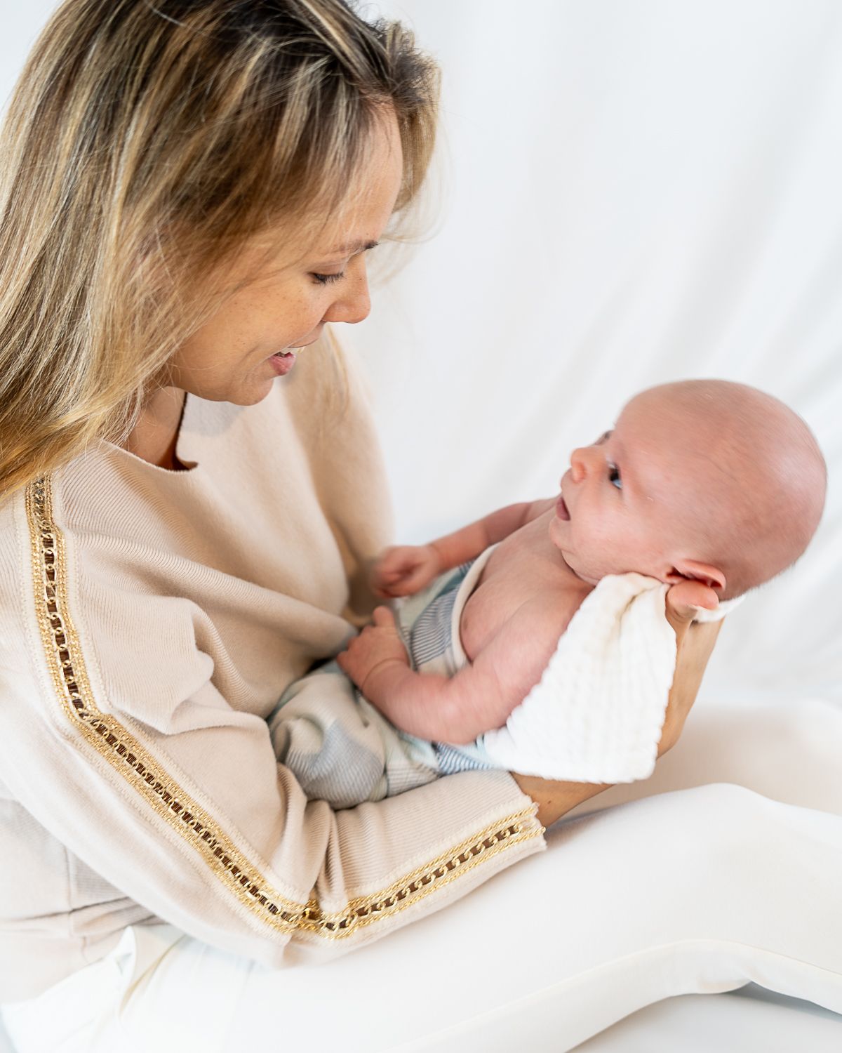 Tender moment between parent and baby in soft white lighting showing gentle affection.