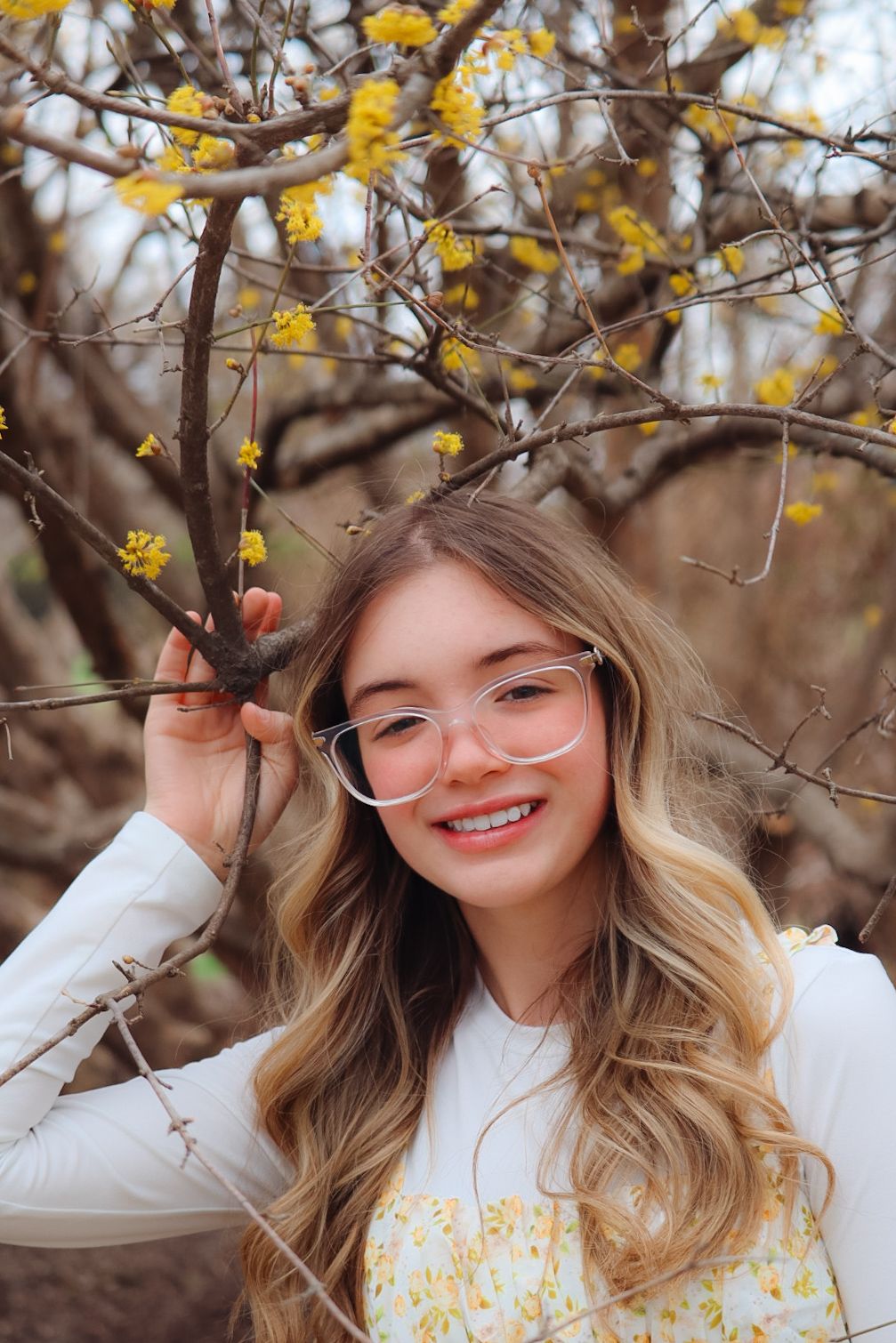 senior girl photoshoot, girl holding a tree branch with yellow flowers