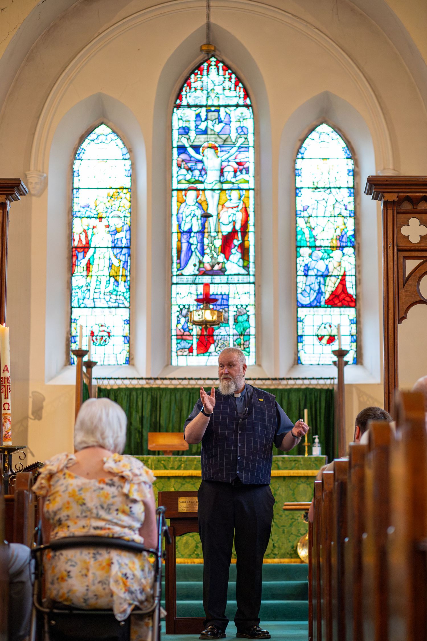 Priest making a speech at a Christening in front of a stained glass window