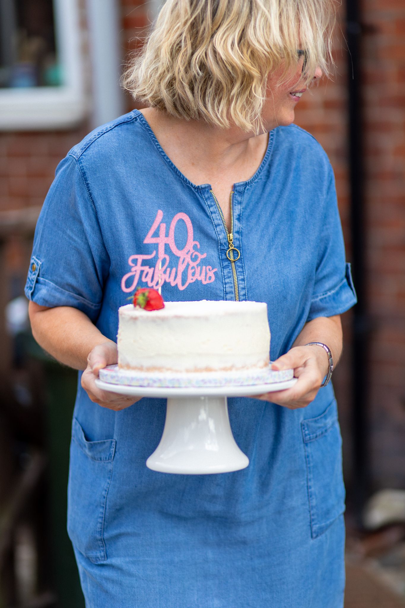Woman holding a 40th Birthday party cake wearing a blue dress