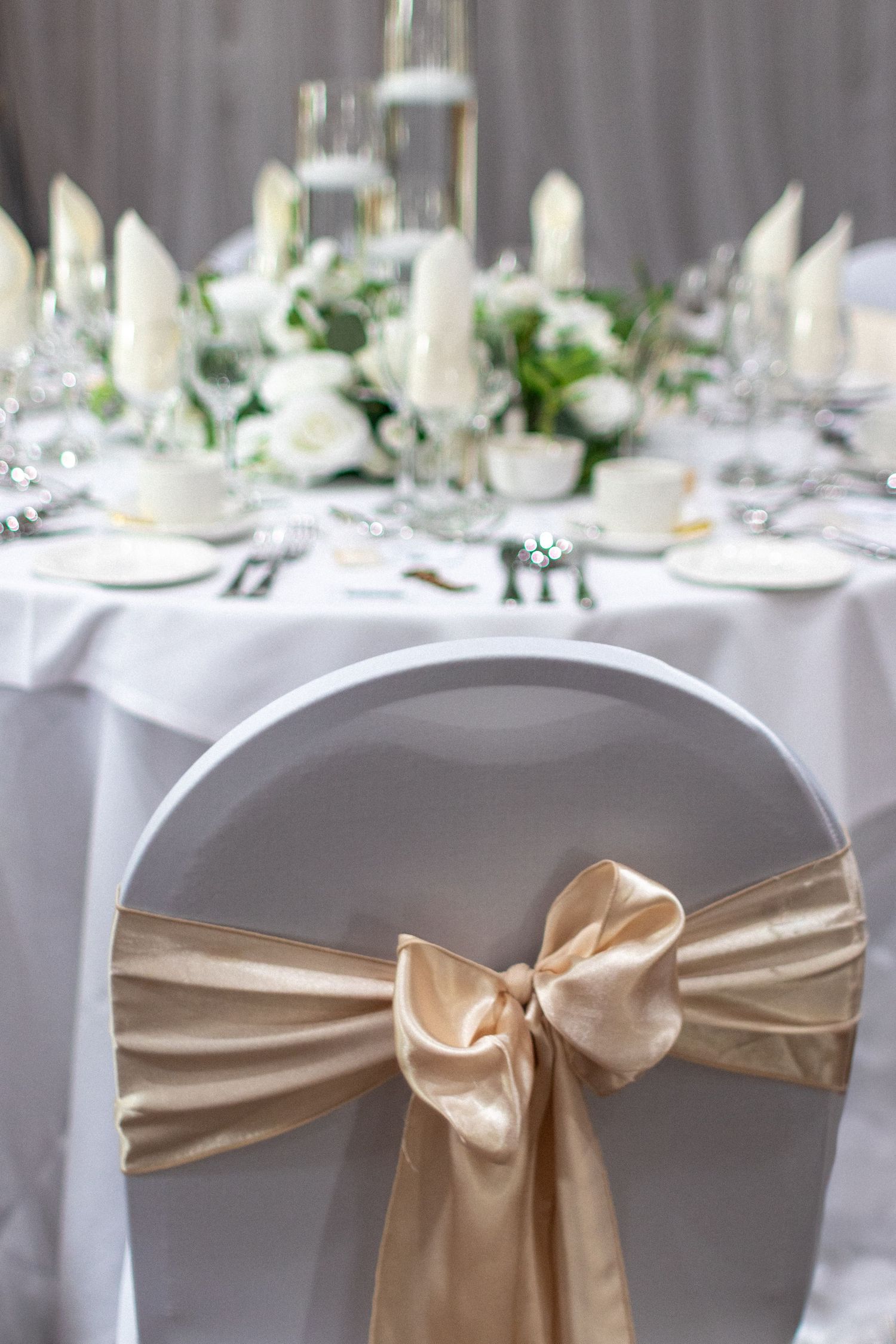 Wedding Reception chairs with white seat covers and golden bows