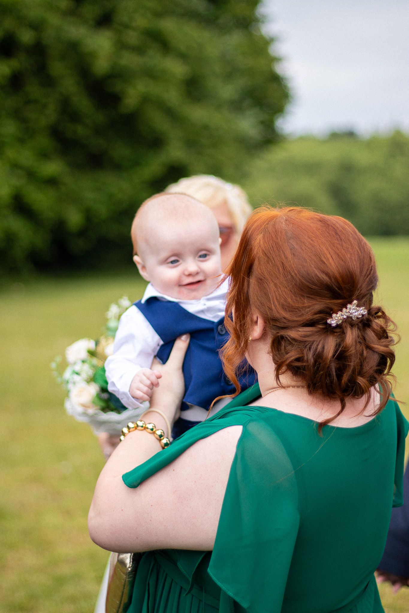 Candid photo of Bridesmaid holding child outdoors