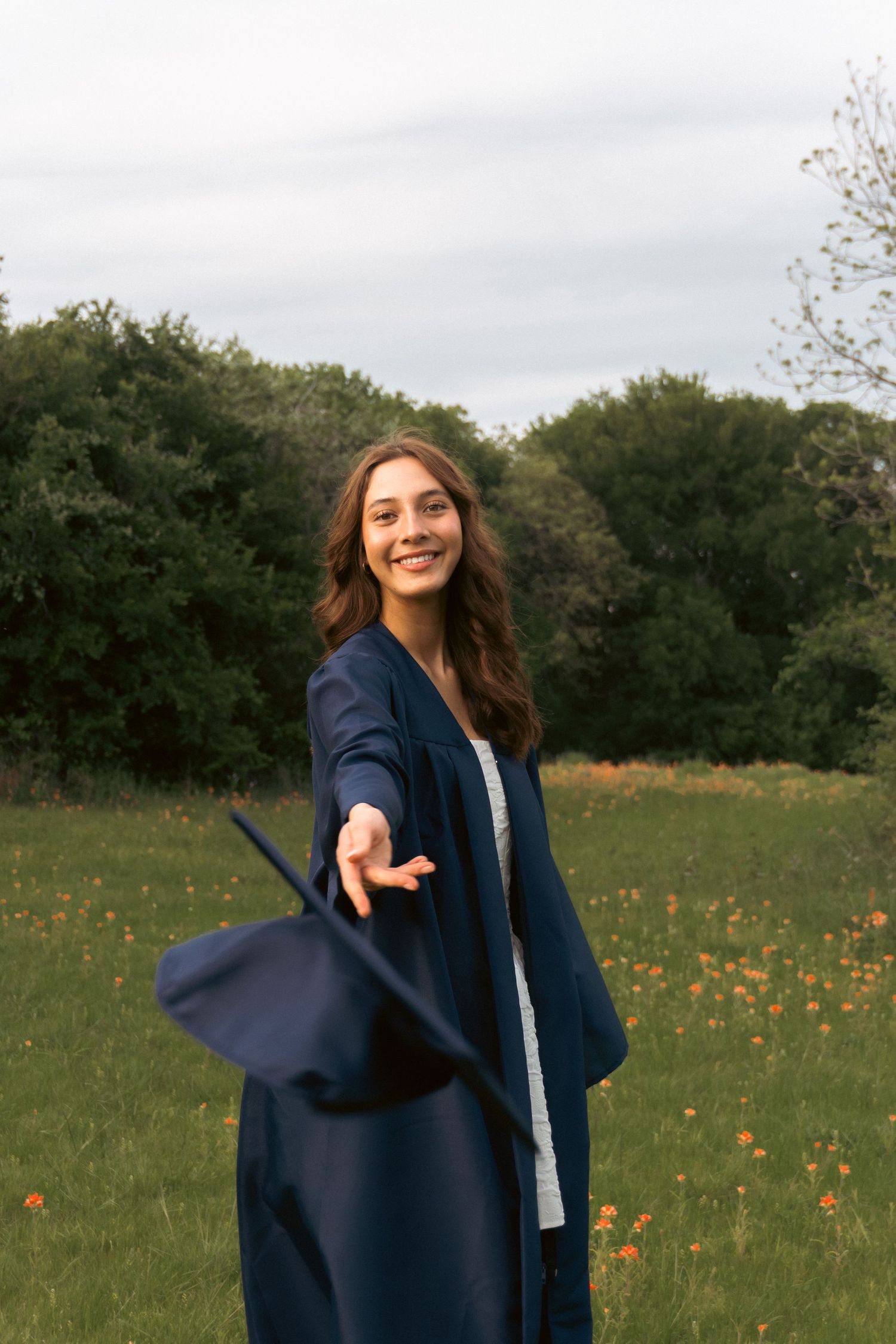 A person in a navy blazer stands in a wildflower meadow with orange blooms on a cloudy day.