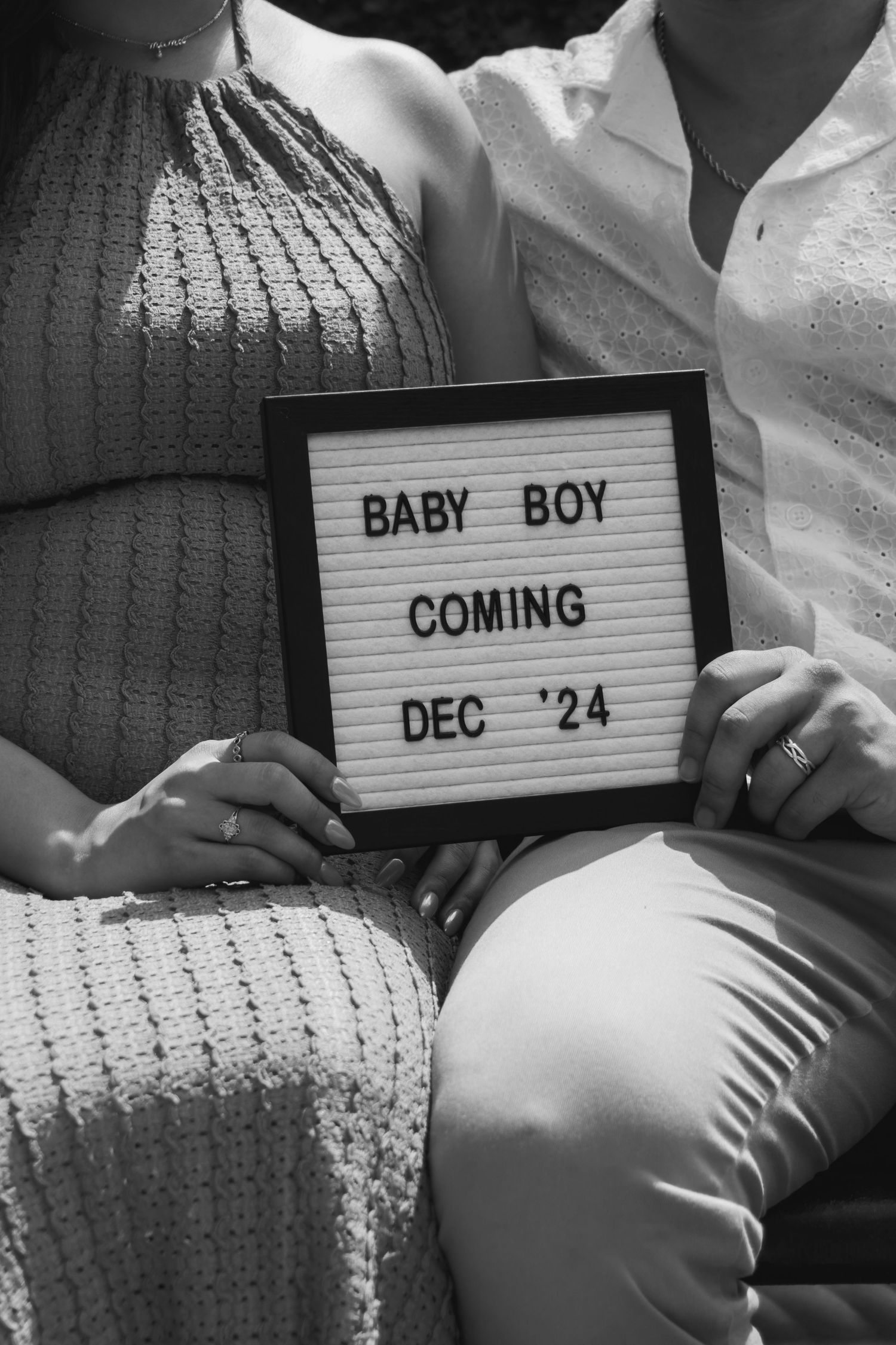Black and white pregnancy announcement photo series showing message boards revealing 'BABY BOY COMING DEC '24'.