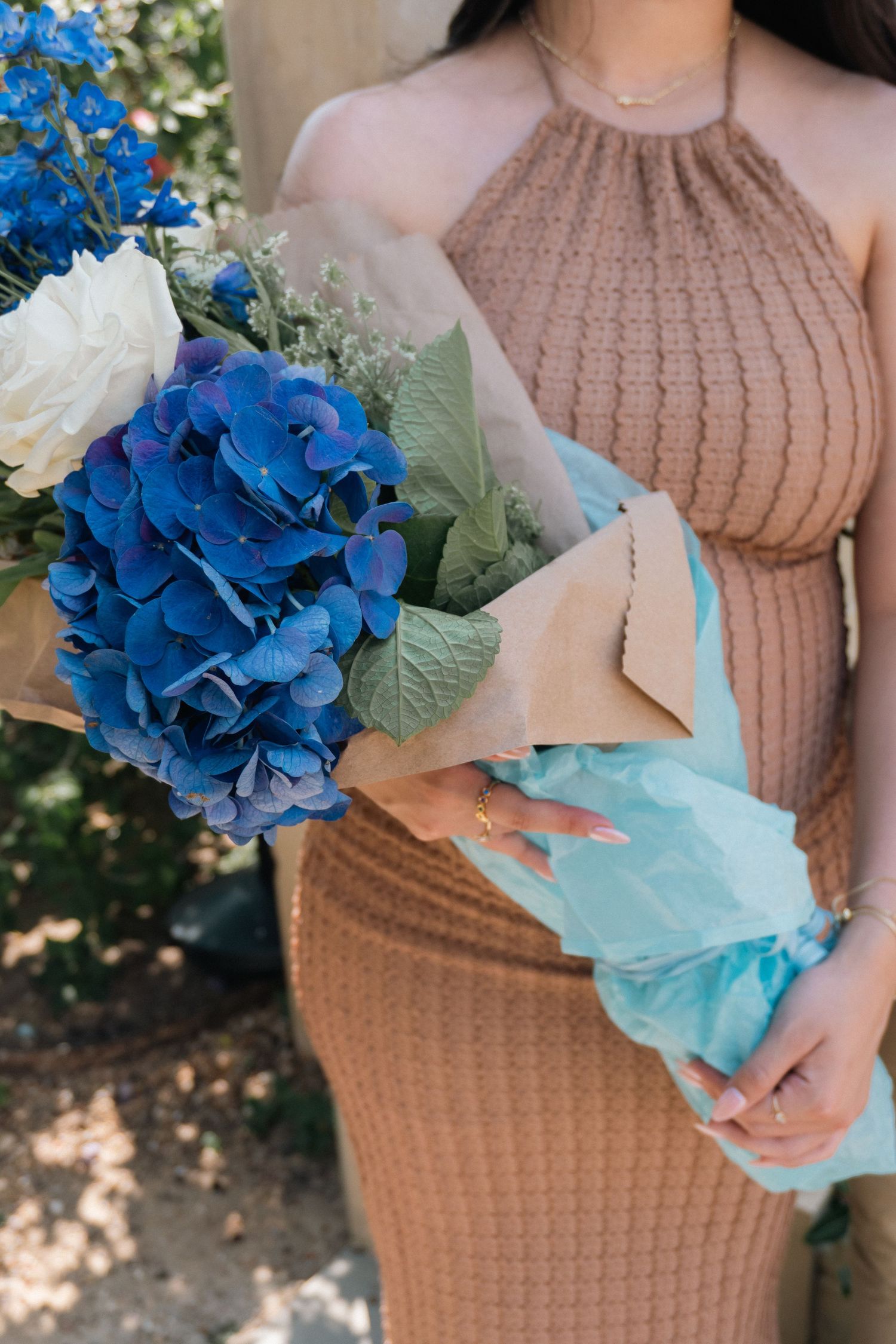 A close-up view of vibrant blue hydrangea flowers wrapped in light blue tissue paper.